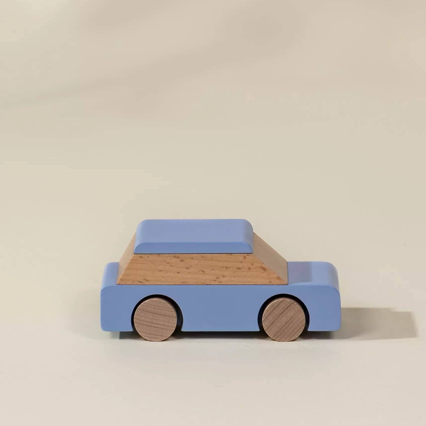 Wooden toy car with blue body and brown wheels on a beige background