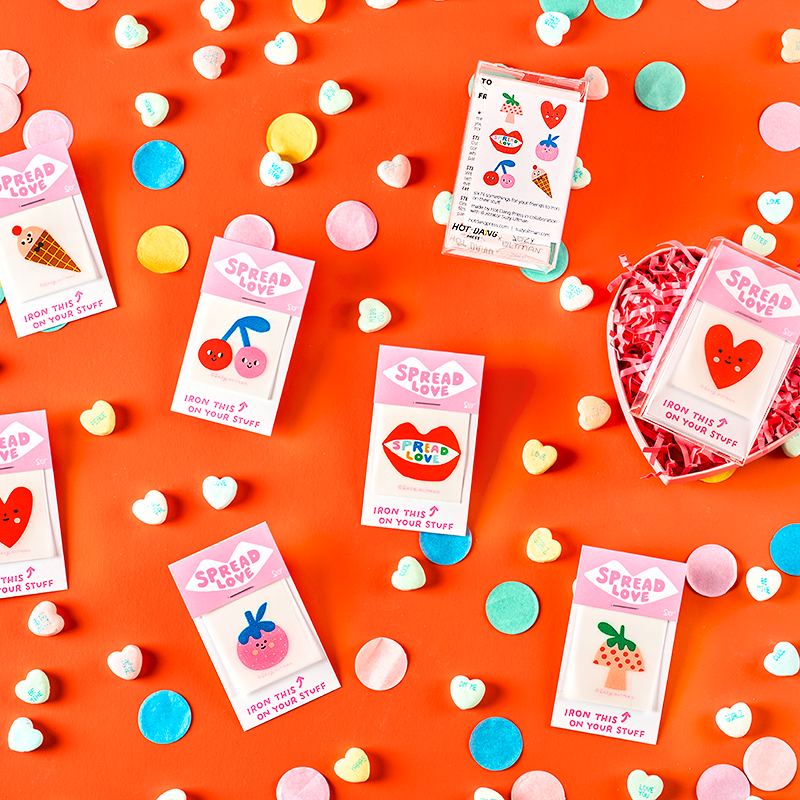 Small packages with colorful labels on a bright orange background with heart-shaped candies.