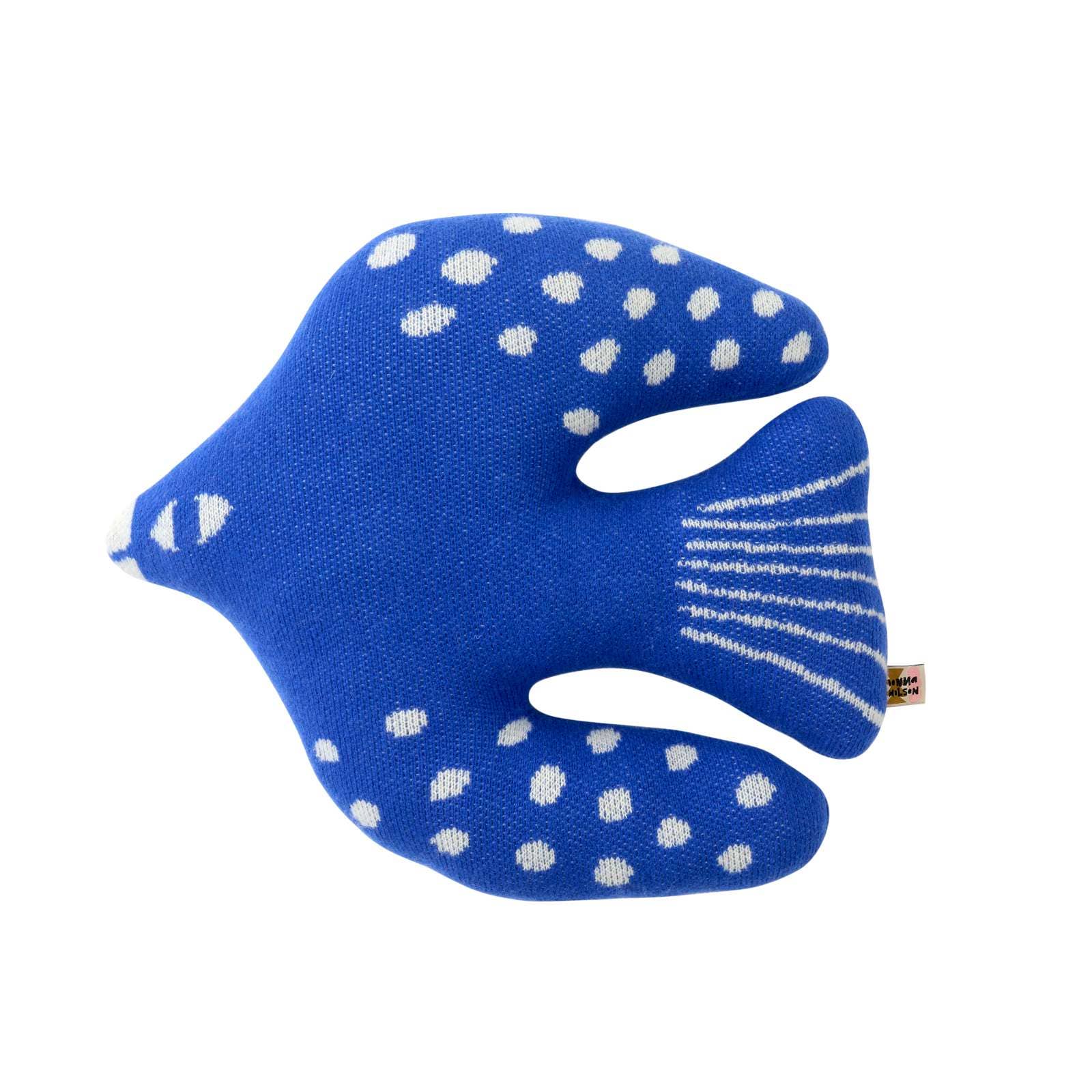 A blue fish-shaped knit cushion with white polka dots and striped detailing, shown on a plain white background.