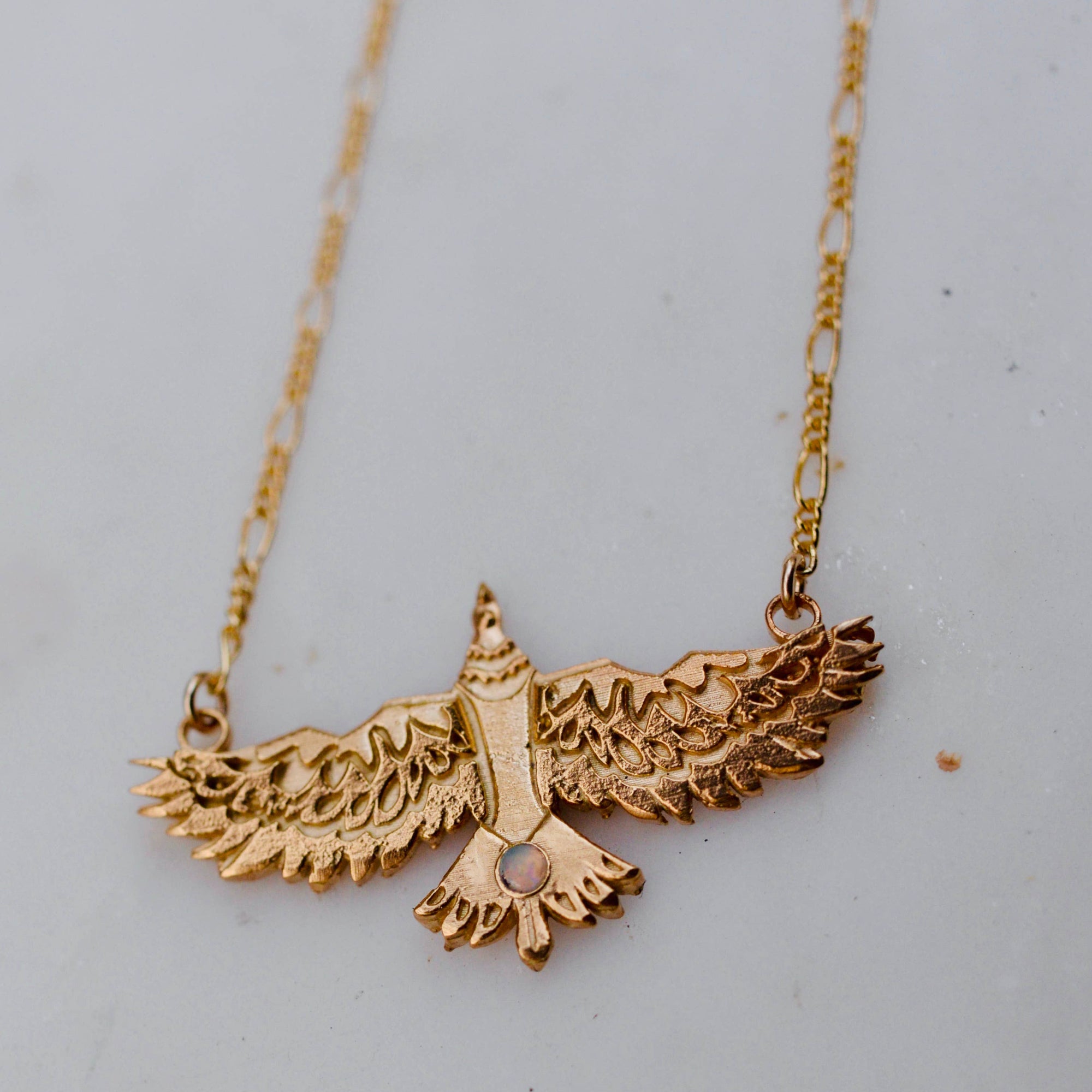 Gold eagle pendant necklace on a light gray background