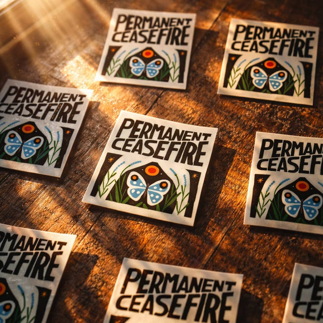 Multiple 'Permanent Ceasefire' stickers on a wooden surface
