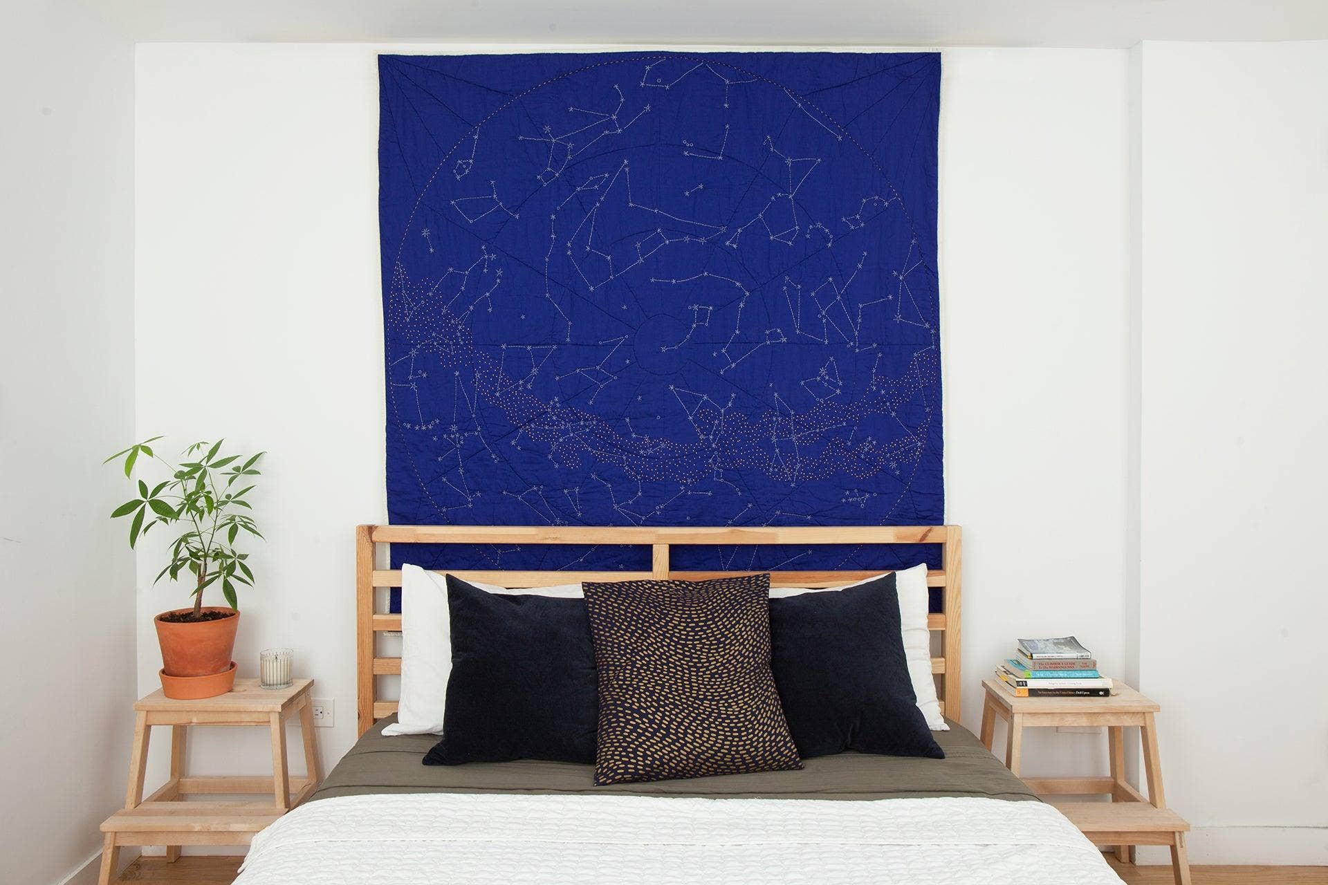 Bedroom with a blue tapestry featuring star constellations on the wall.