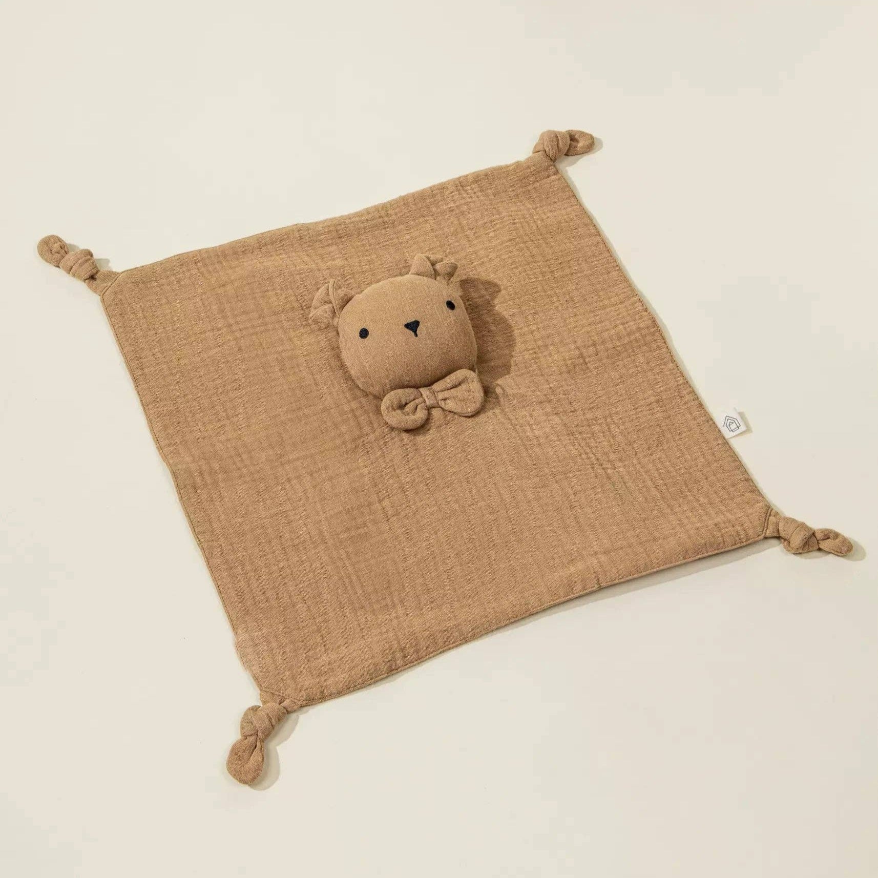 Brown textured cloth square with a plush toy on a beige background