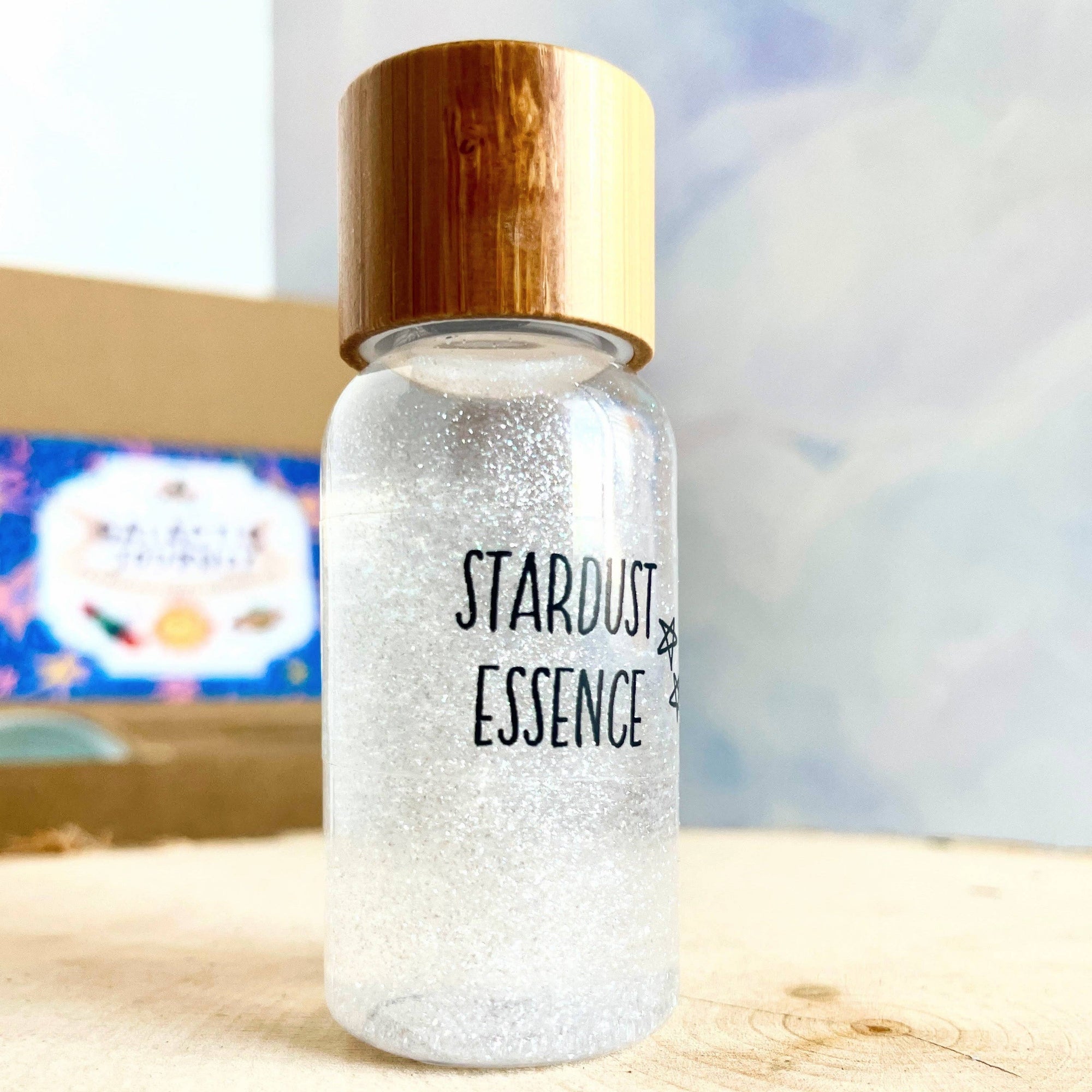 Bottle labeled 'Stardust Essence' with a wood cap on a wooden surface.