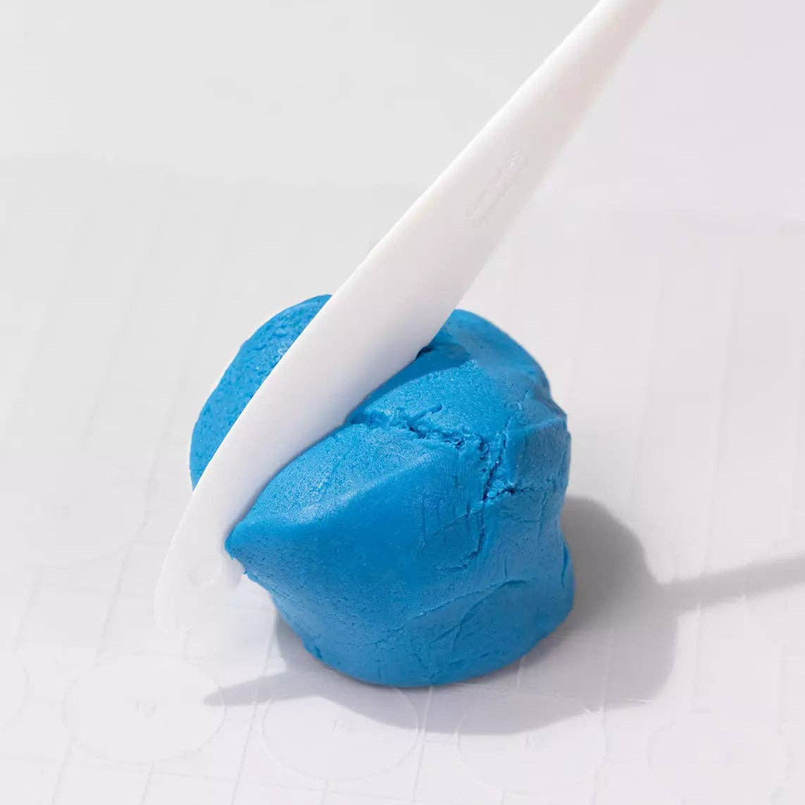Blue clay ball with a white stick on a white background