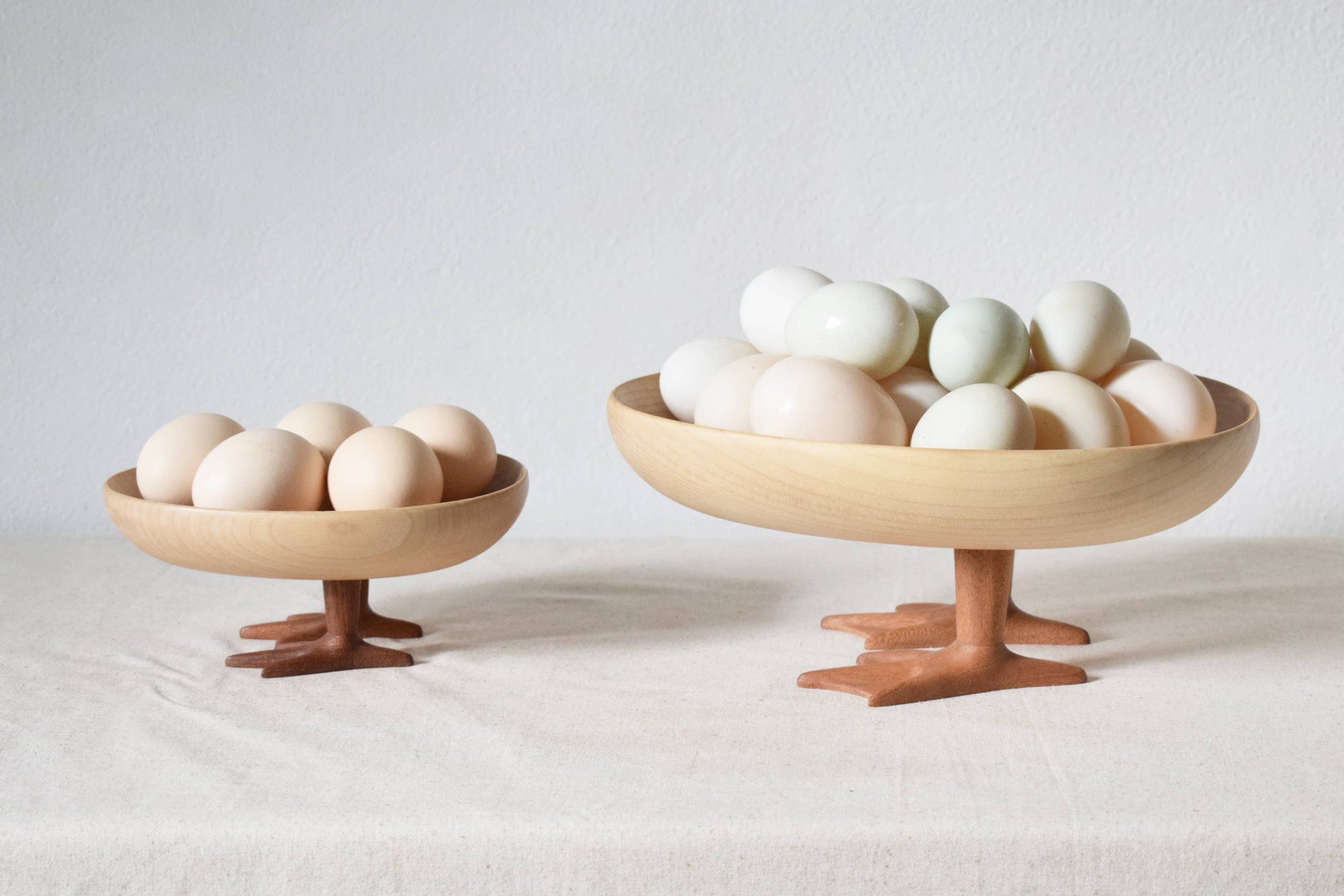 Two wooden bowls with eggs on a light background