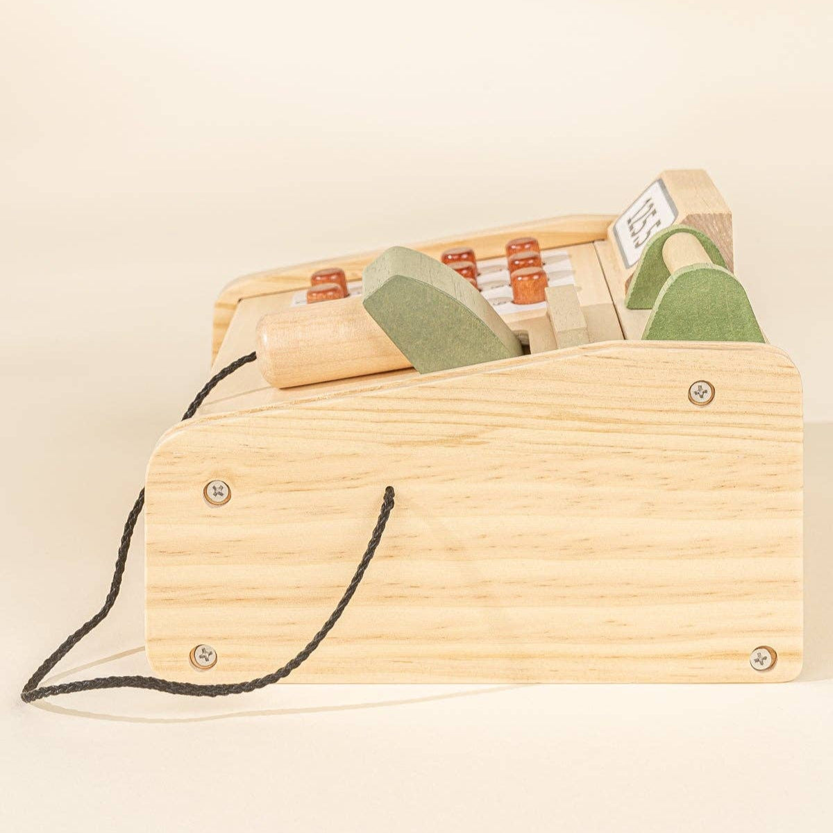 Wooden toy register with green and brown items on a beige background