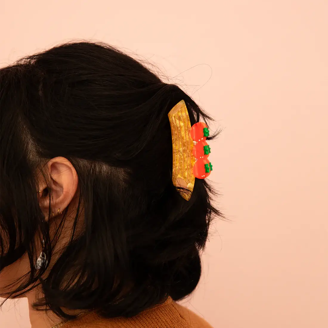 Close-up of a person's hair with a decorative barrette against a pink background