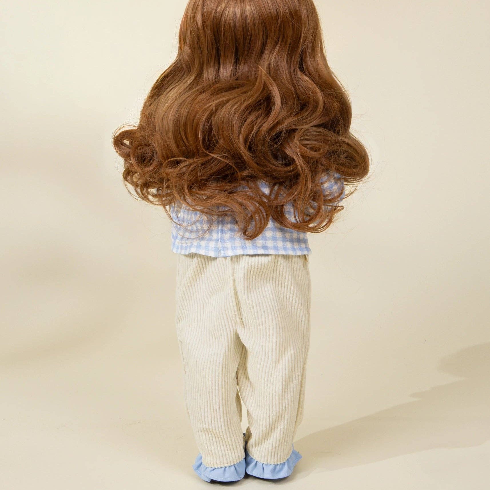 doll wearing a wig with long, wavy brown hair on a plain background