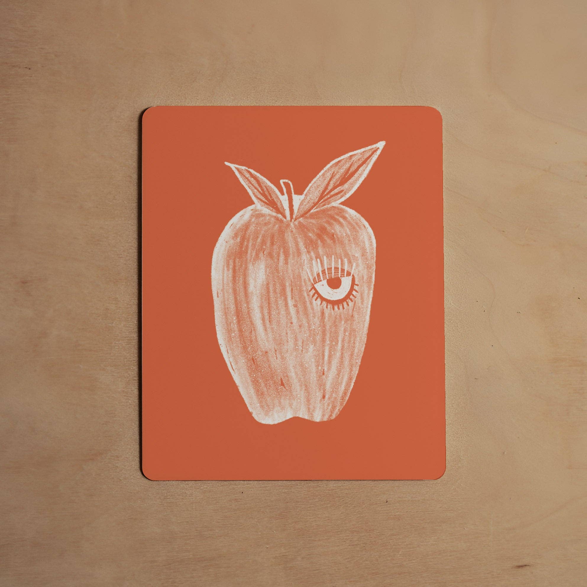 Notebook with a white apple illustration on a red cover, placed on a wooden surface.