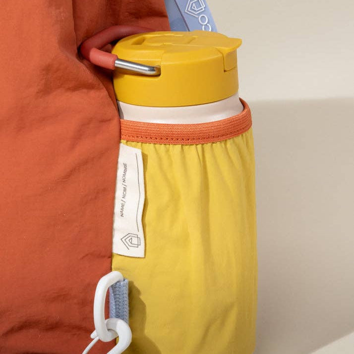 Yellow water bottle with orange accents and a white label against a neutral background