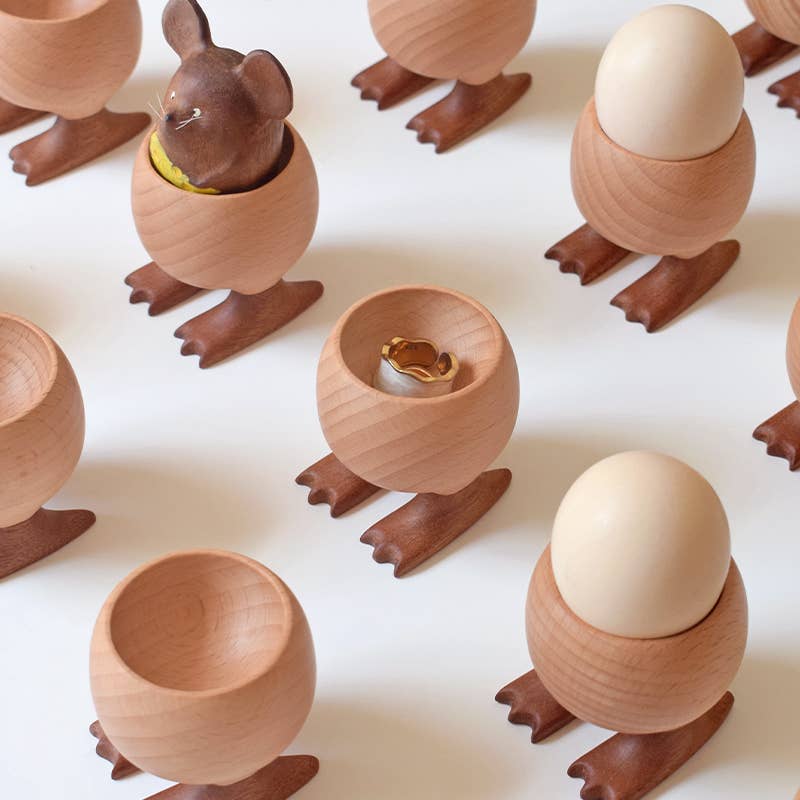 Wooden duck-shaped egg holders with eggs on a white background