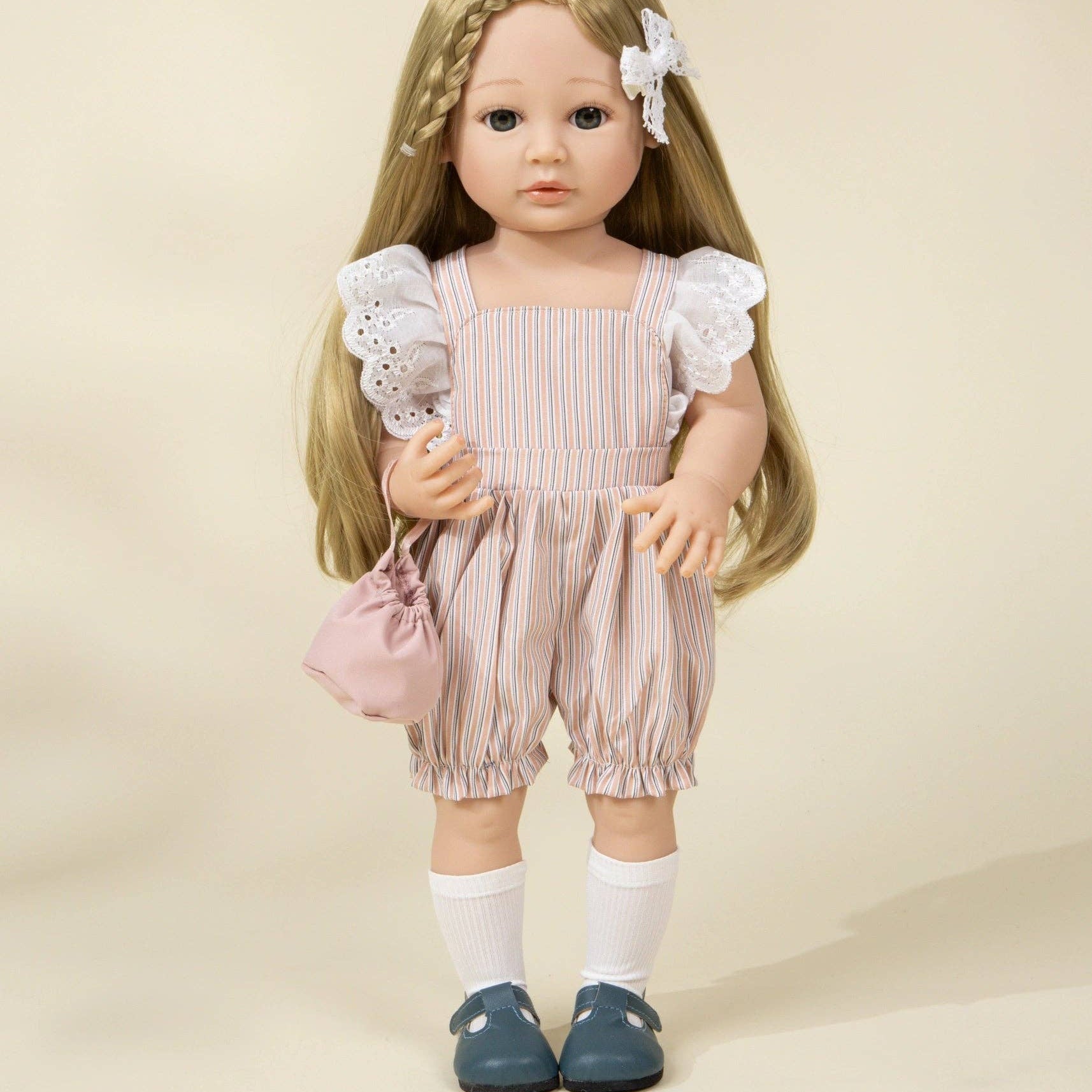 Doll with long blonde hair wearing a pink outfit against a beige background