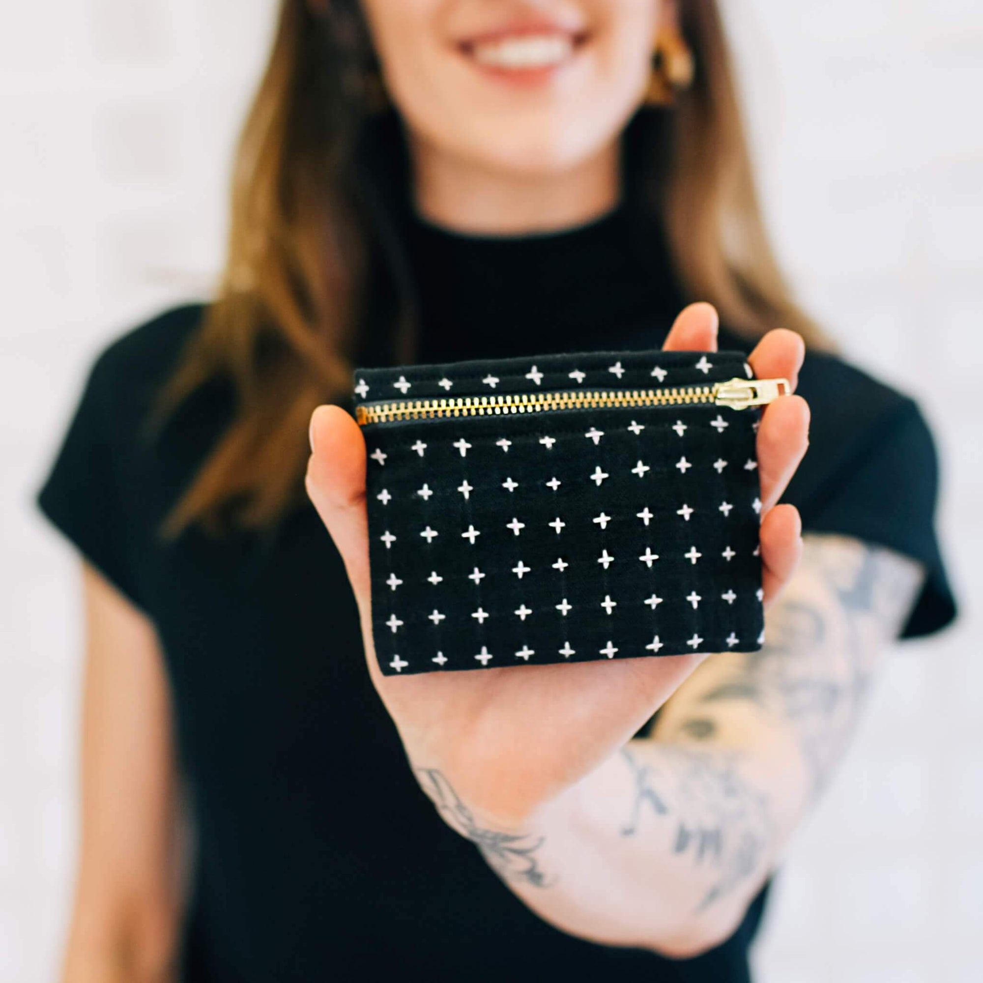 Person holding a black pouch with white star patterns and a gold zipper.