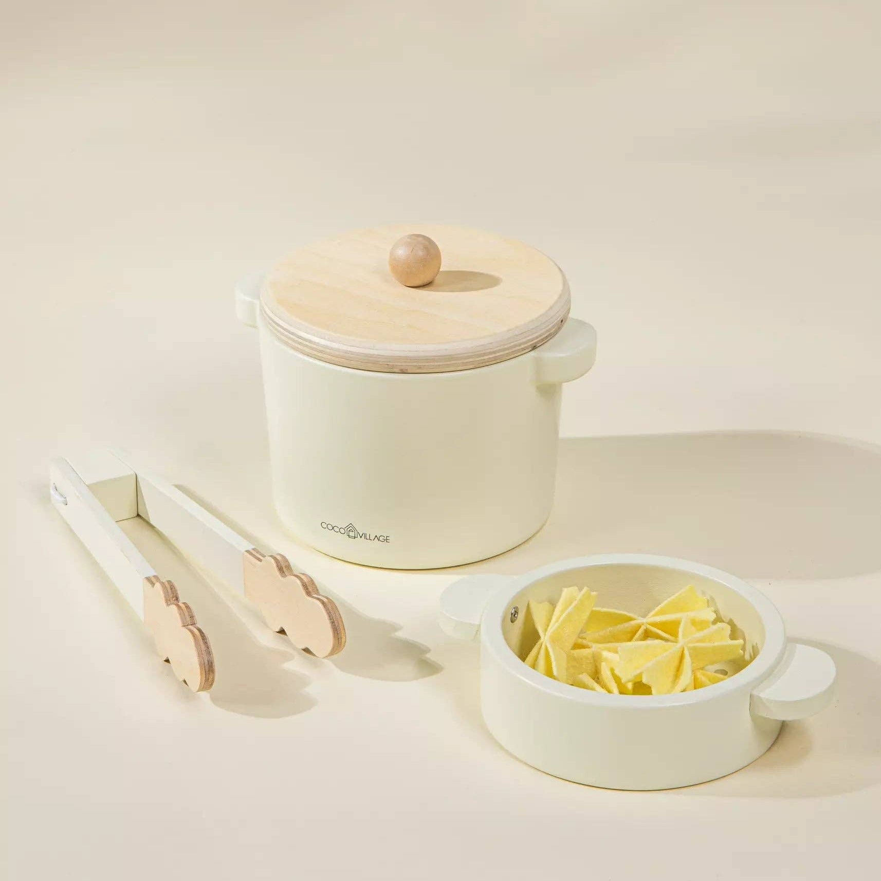 Small white appliance with a lid, tongs, and a bowl of pasta on a light background