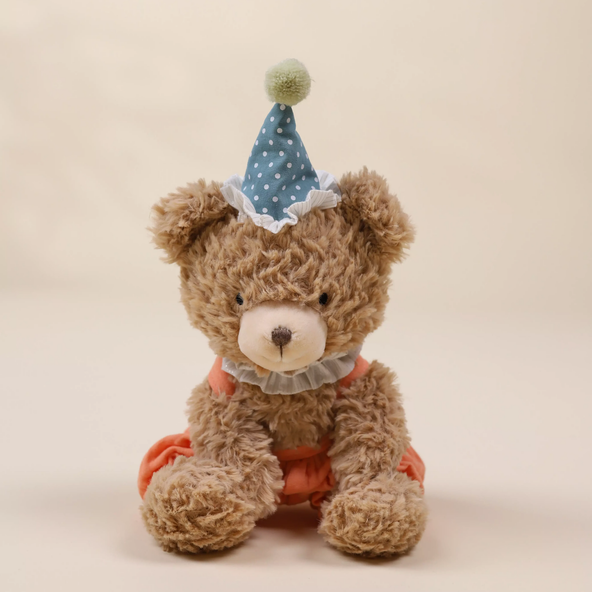 Teddy bear wearing a party hat on a beige background