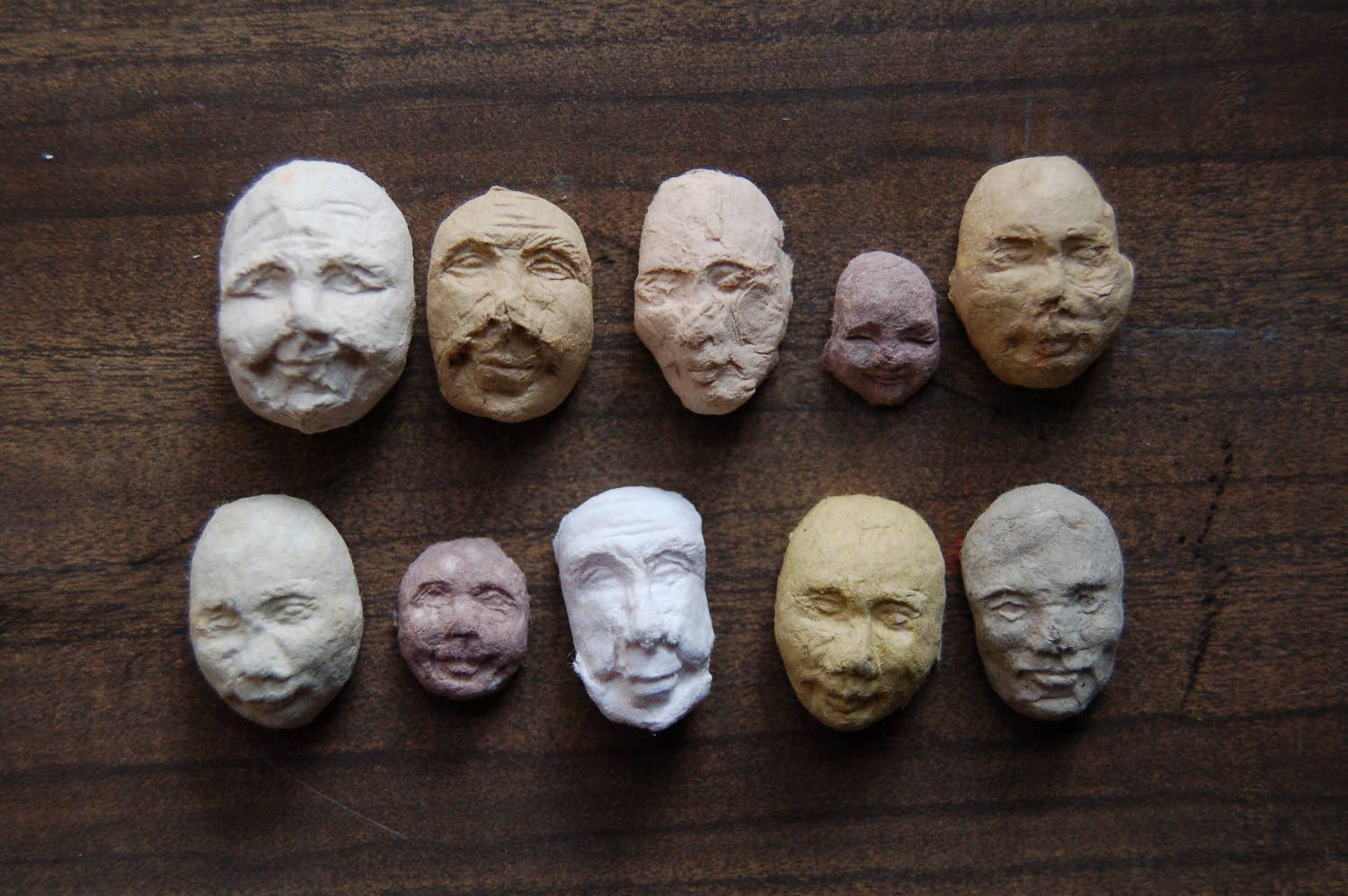 Row of paper face sculptures on a wooden surface
