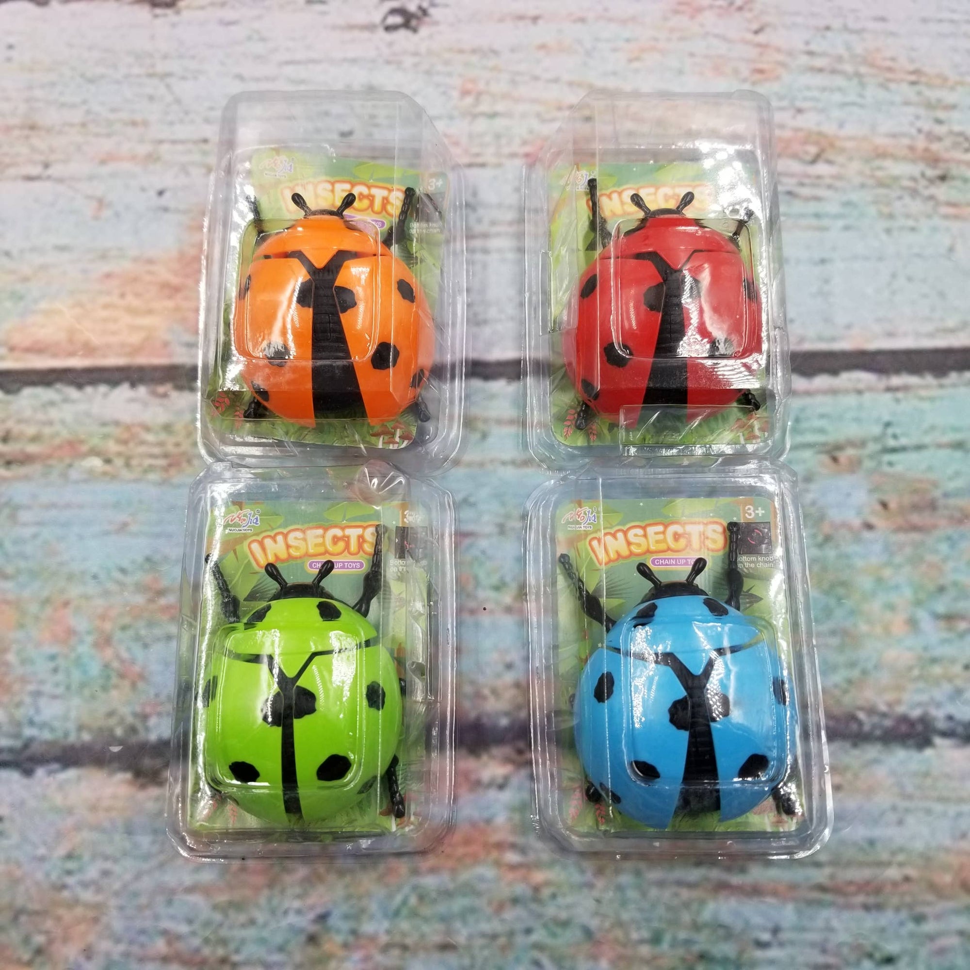 Four plastic packages containing ladybug-shaped toys on a textured surface.