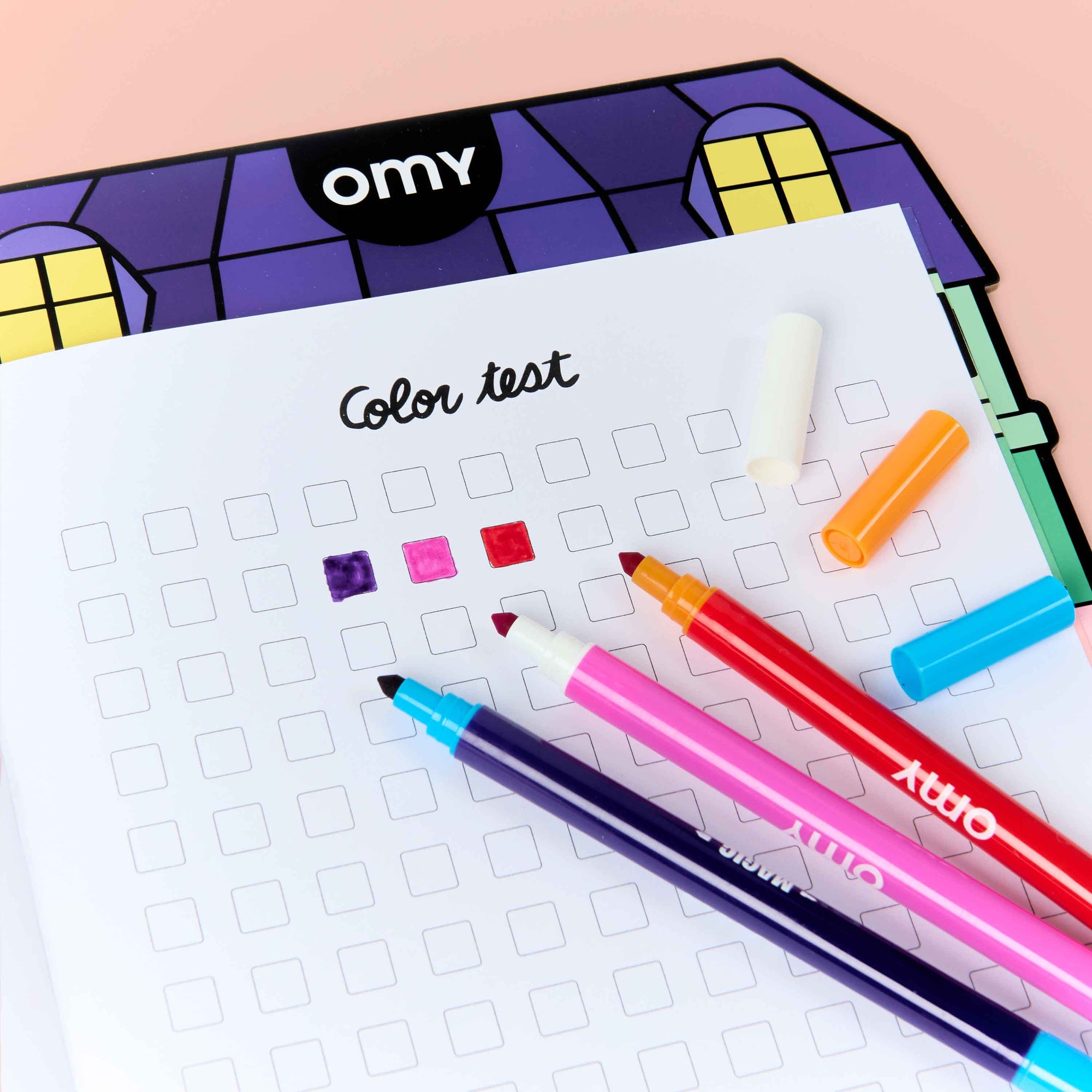 Color swatches and markers on a sheet of paper with 'omy' branding.