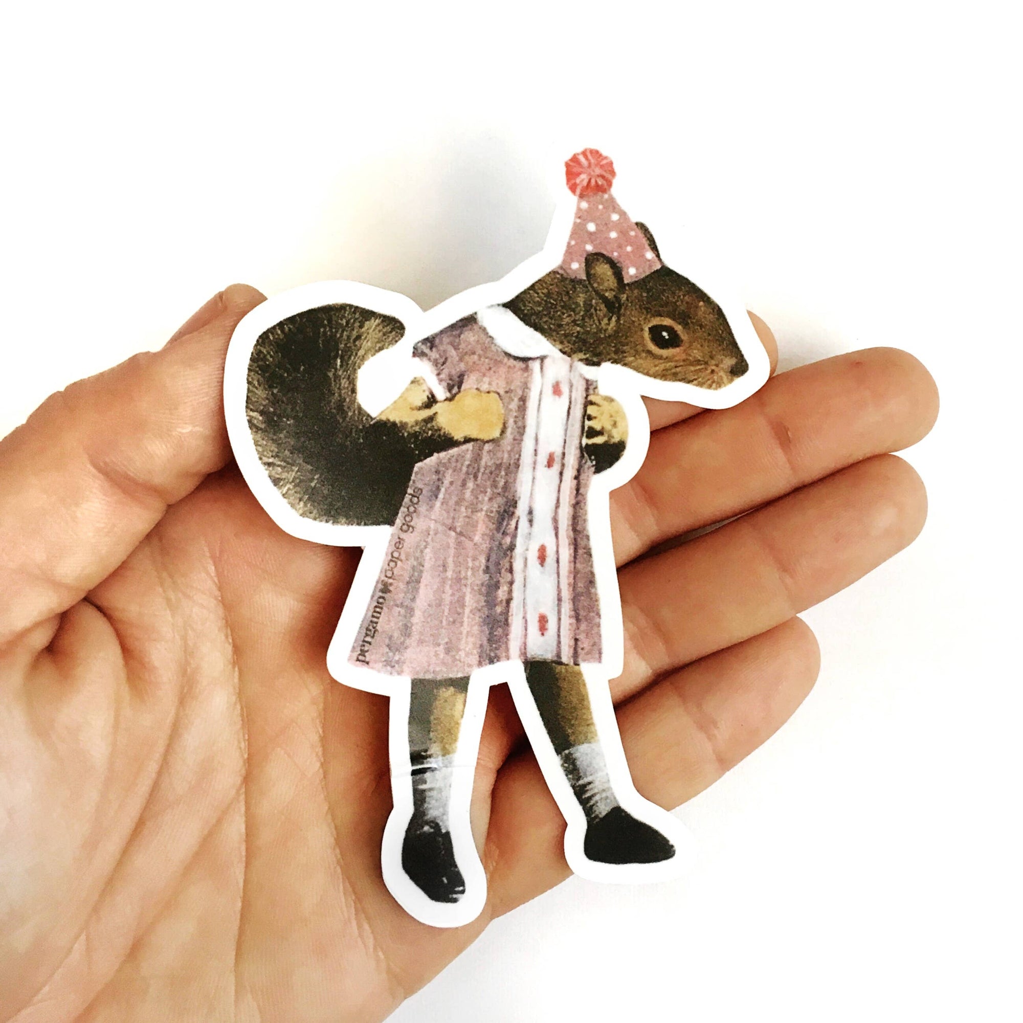 Sticker of a squirrel in a coat and hat held between fingers