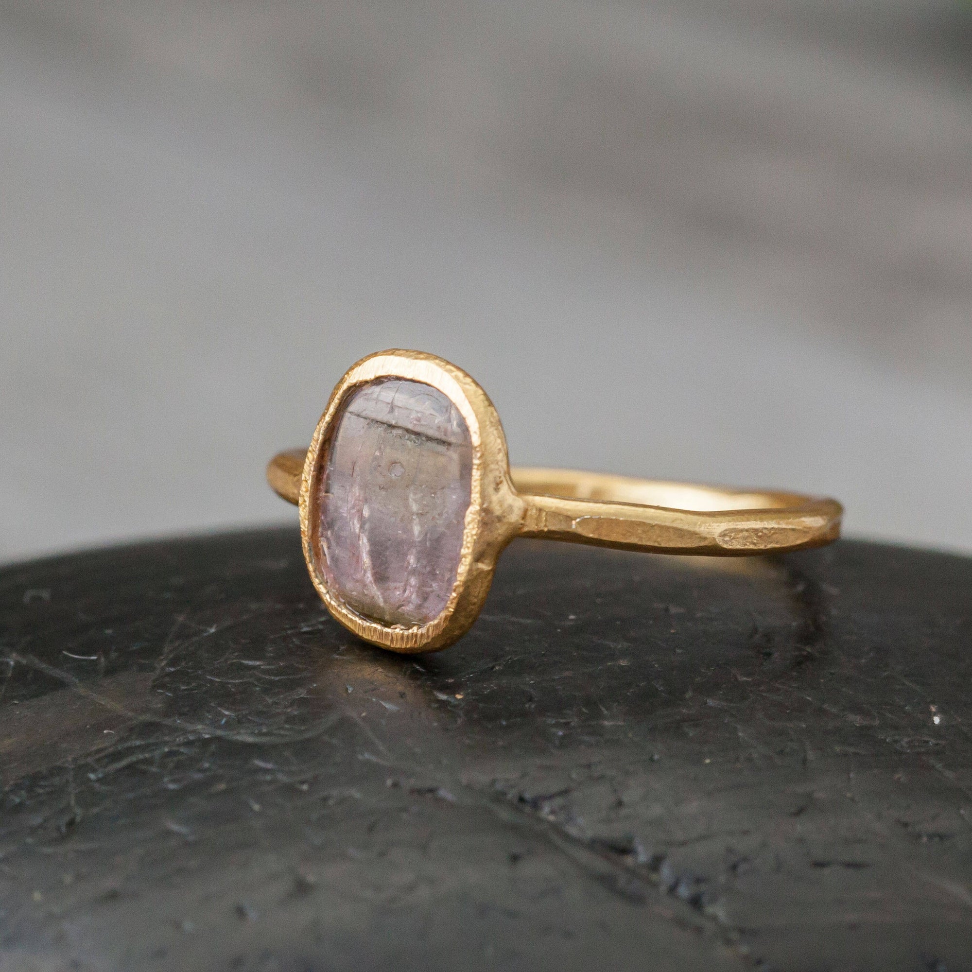 Gold ring with a purple stone on a dark surface