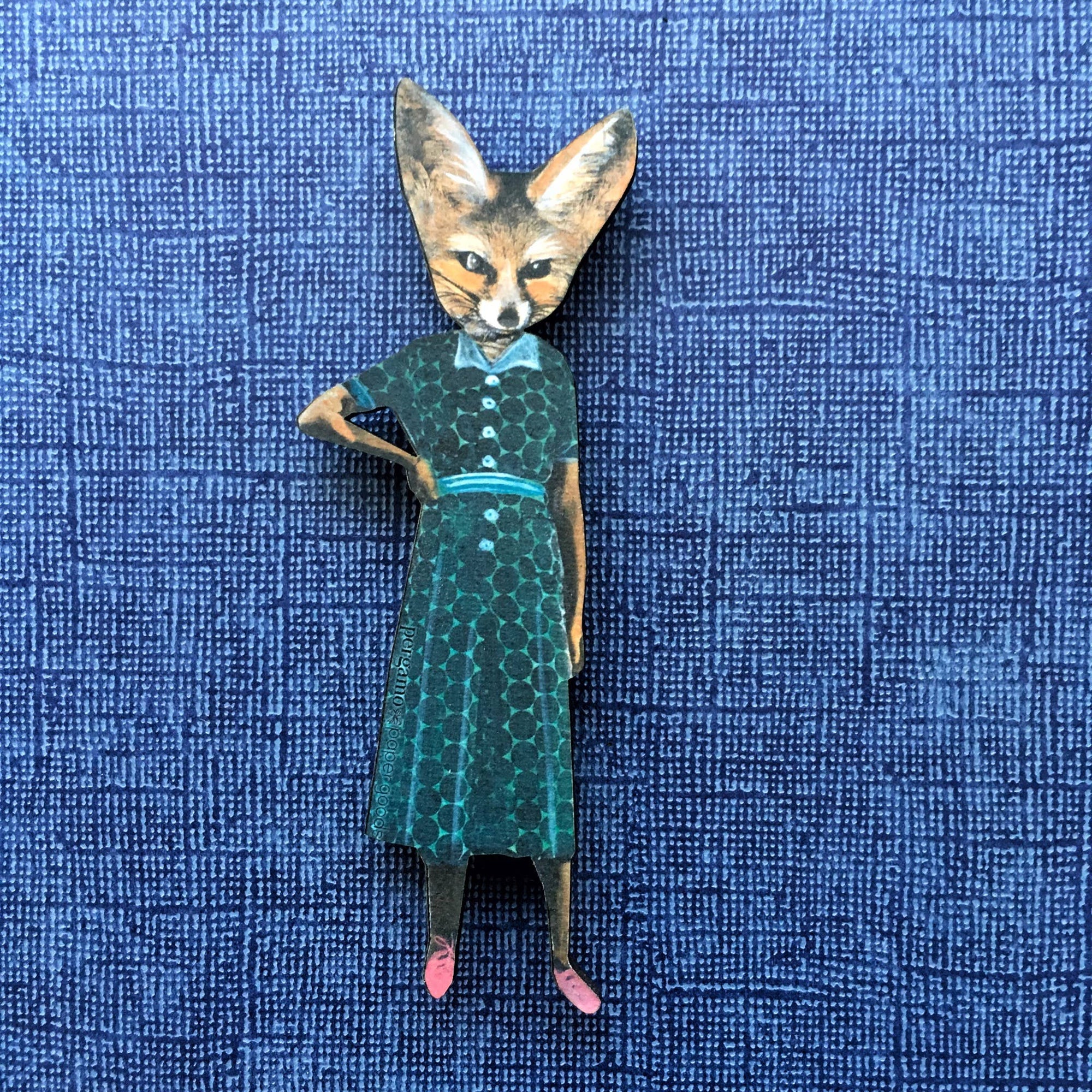 Fox figurine wearing a green dress on a blue textured background
