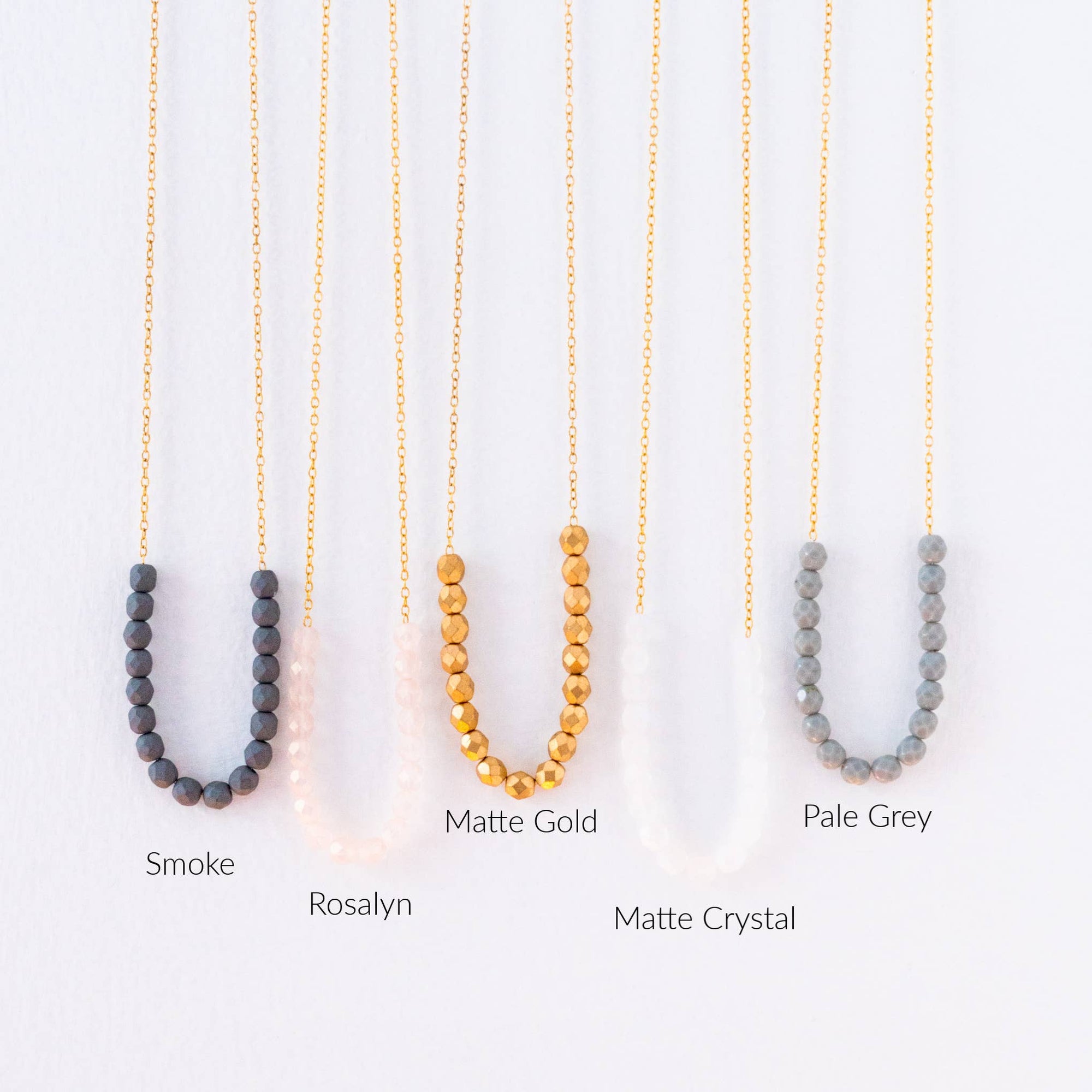 Three beaded necklaces in Smoke, Rosalyn, and Pale Grey on a white background