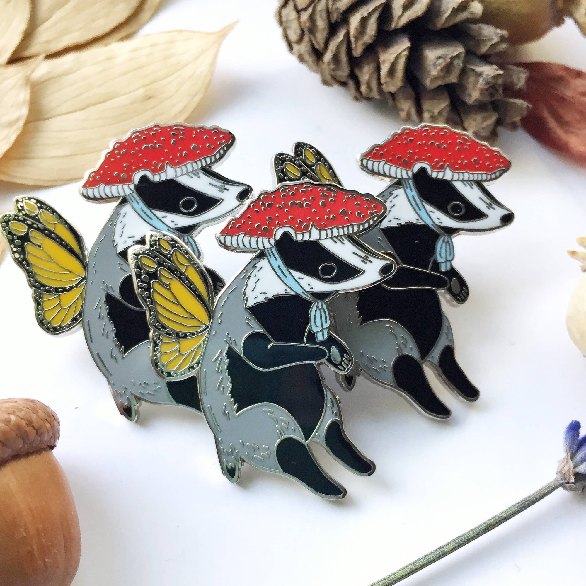Badger pins with mushroom hats on a white surface with natural elements.
