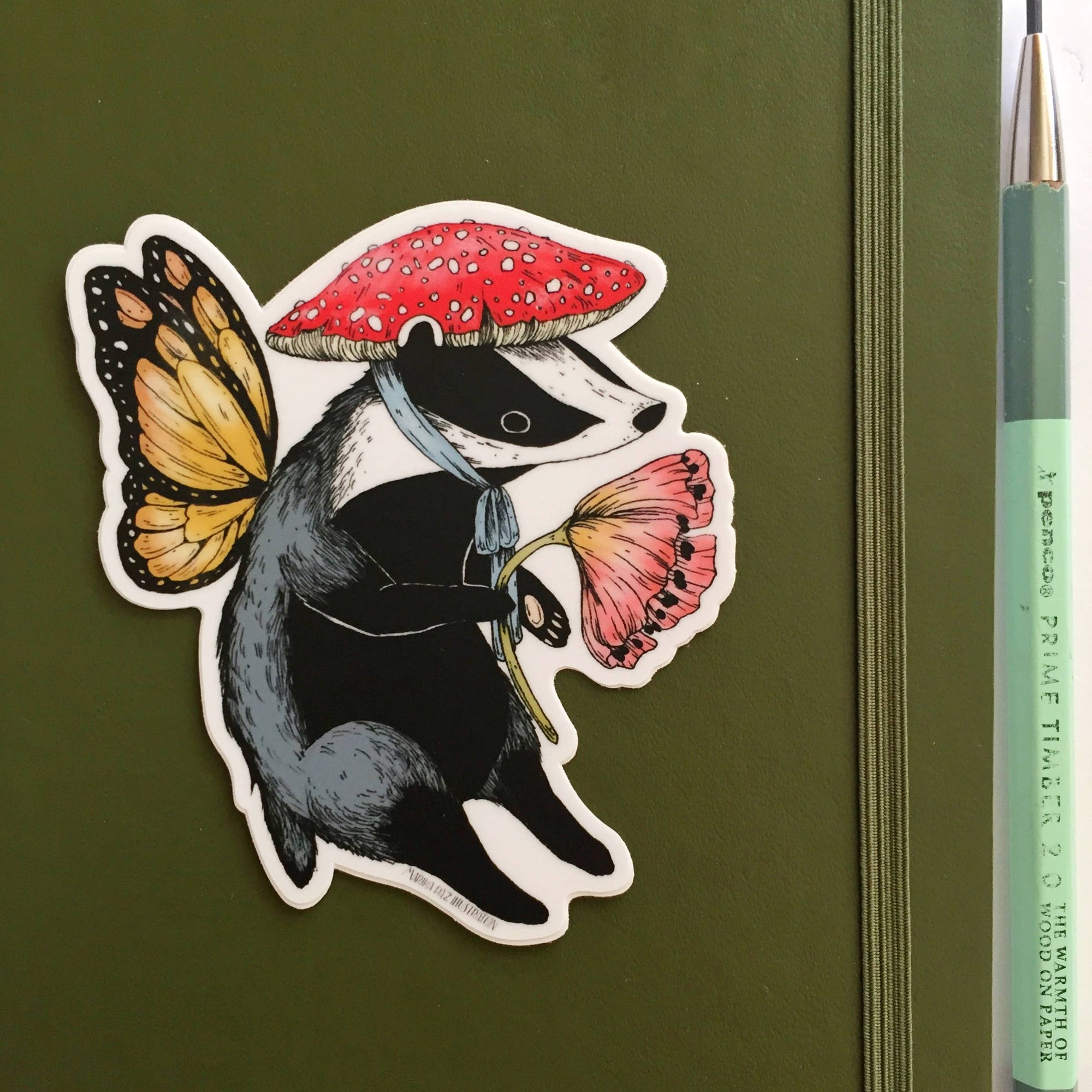 Sticker of a badger with a mushroom and butterfly on a green notebook