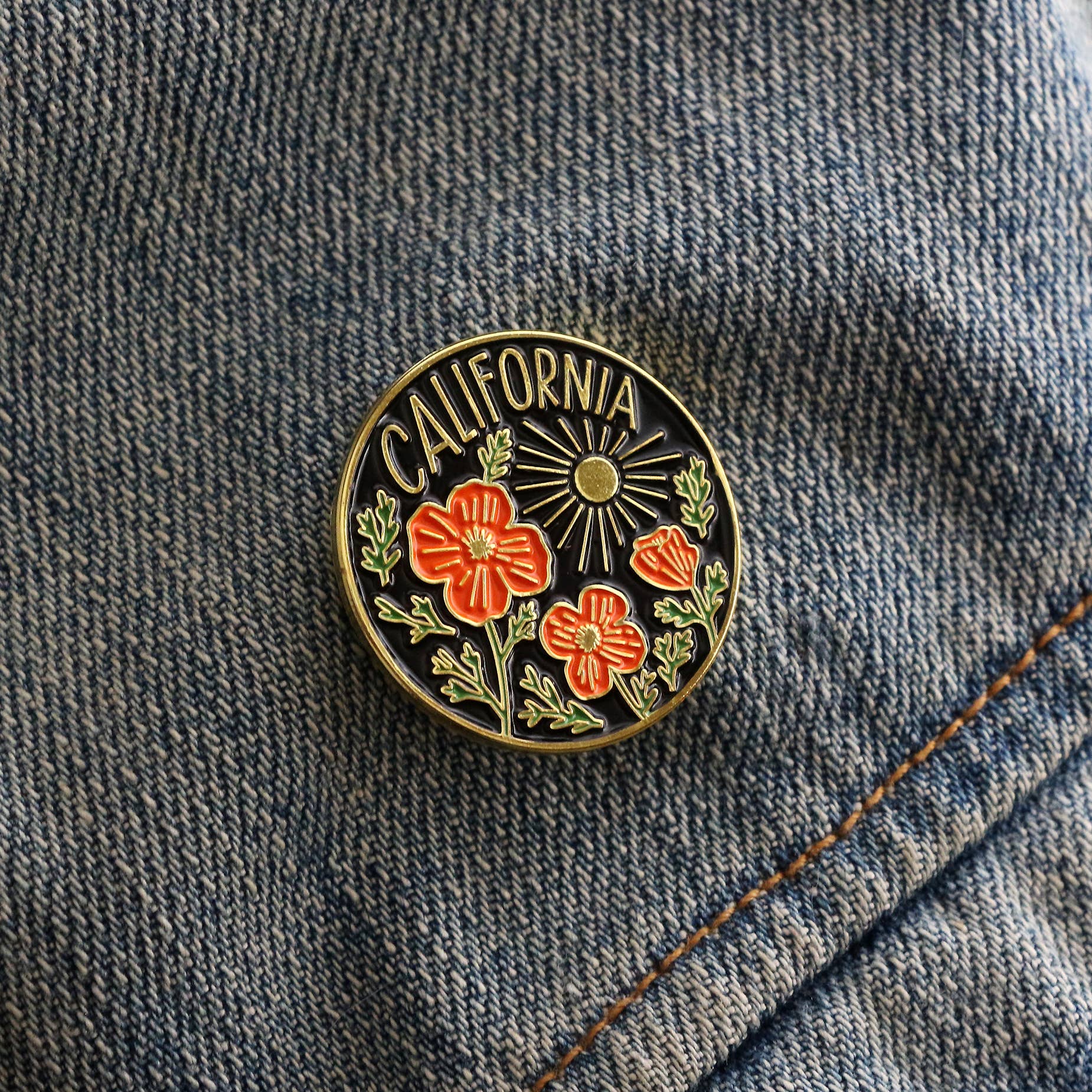 Pin with 'California' text and floral design on a denim background