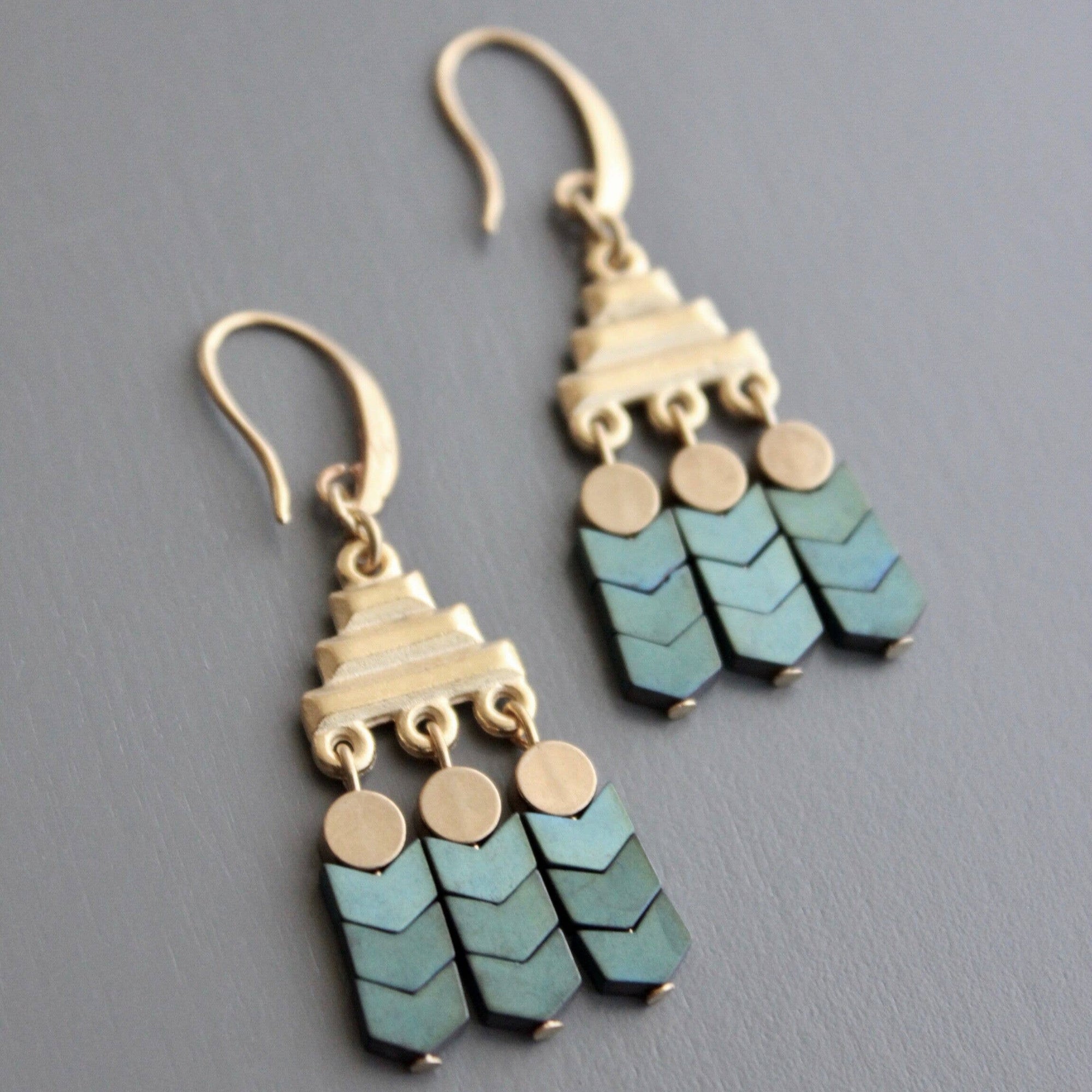 Pair of earrings with green and gold chevron patterns on a gray background