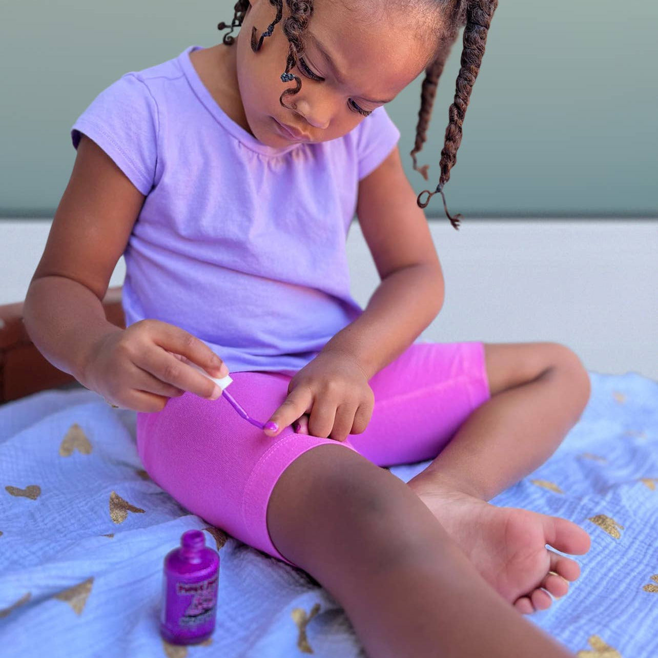 Child applying sunscreen to their leg on a blanket