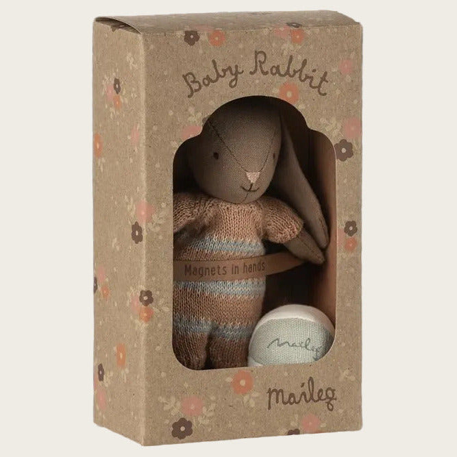 A baby rabbit plush toy inside its decorative kraft paper packaging box, featuring a window cutout showing the stuffed bunny and a small white ball, with floral patterns on the box.