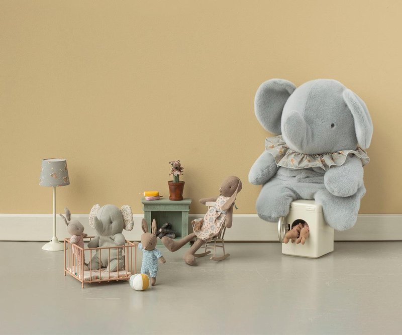 Children's playroom with stuffed toys including a large gray elephant, rabbit, and bear on a beige floor and wall.