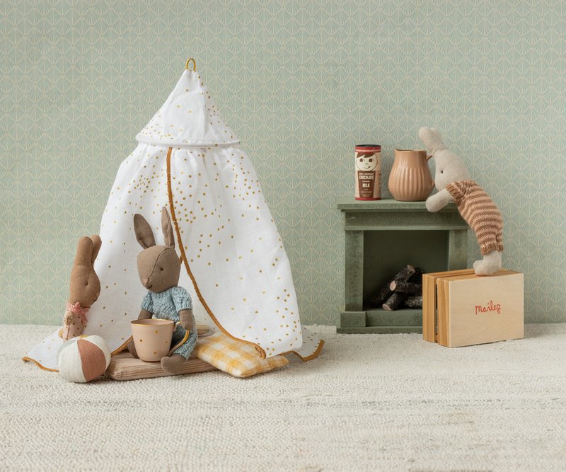 Children's play area with a small tent, toys, and a book on a textured surface.