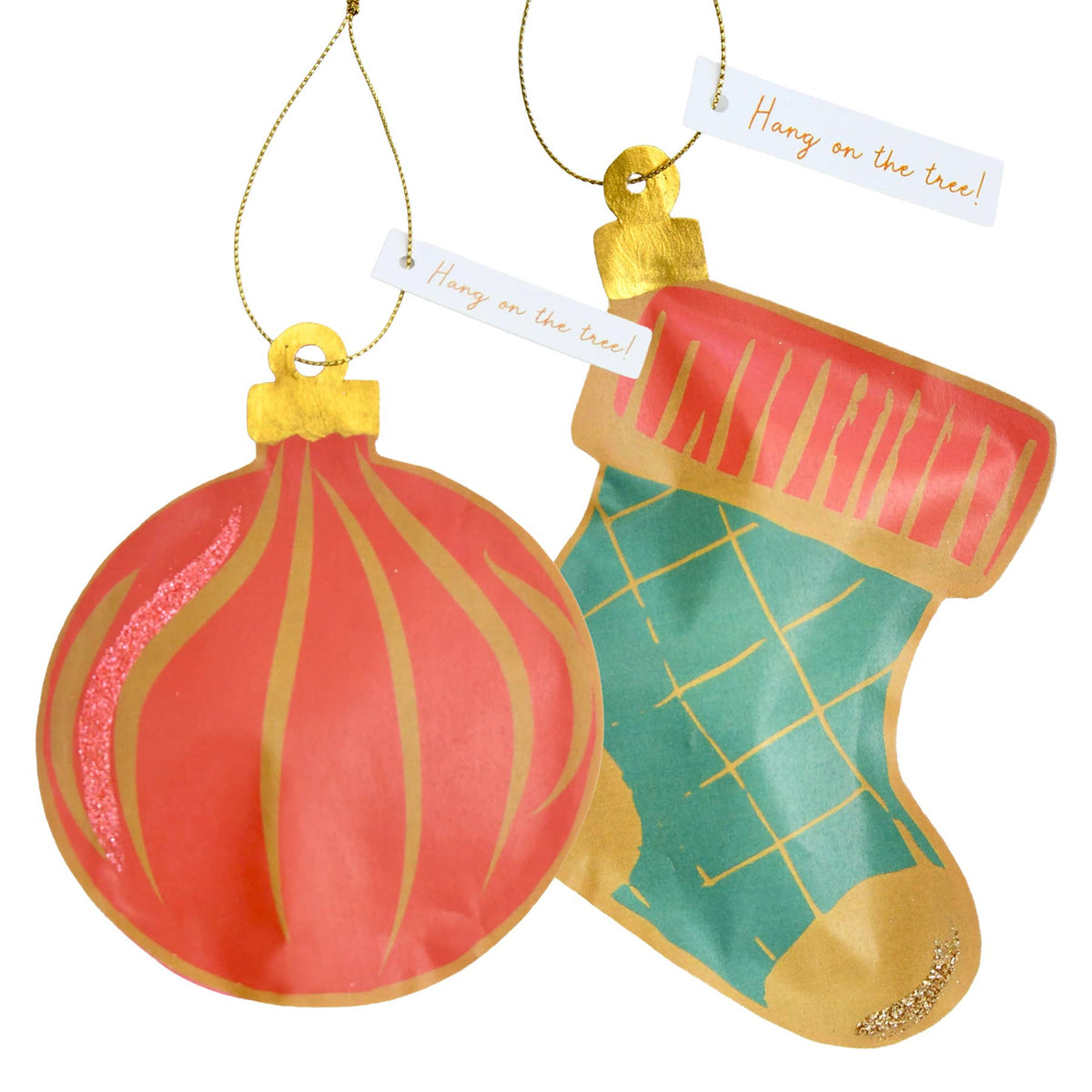 Two Christmas tree ornaments on a white background: a round coral-red ornament with gold stripes and a stocking ornament in coral-red and teal with gold grid lines and gold hanging loops and tags that read 'Hang on the tree!'.