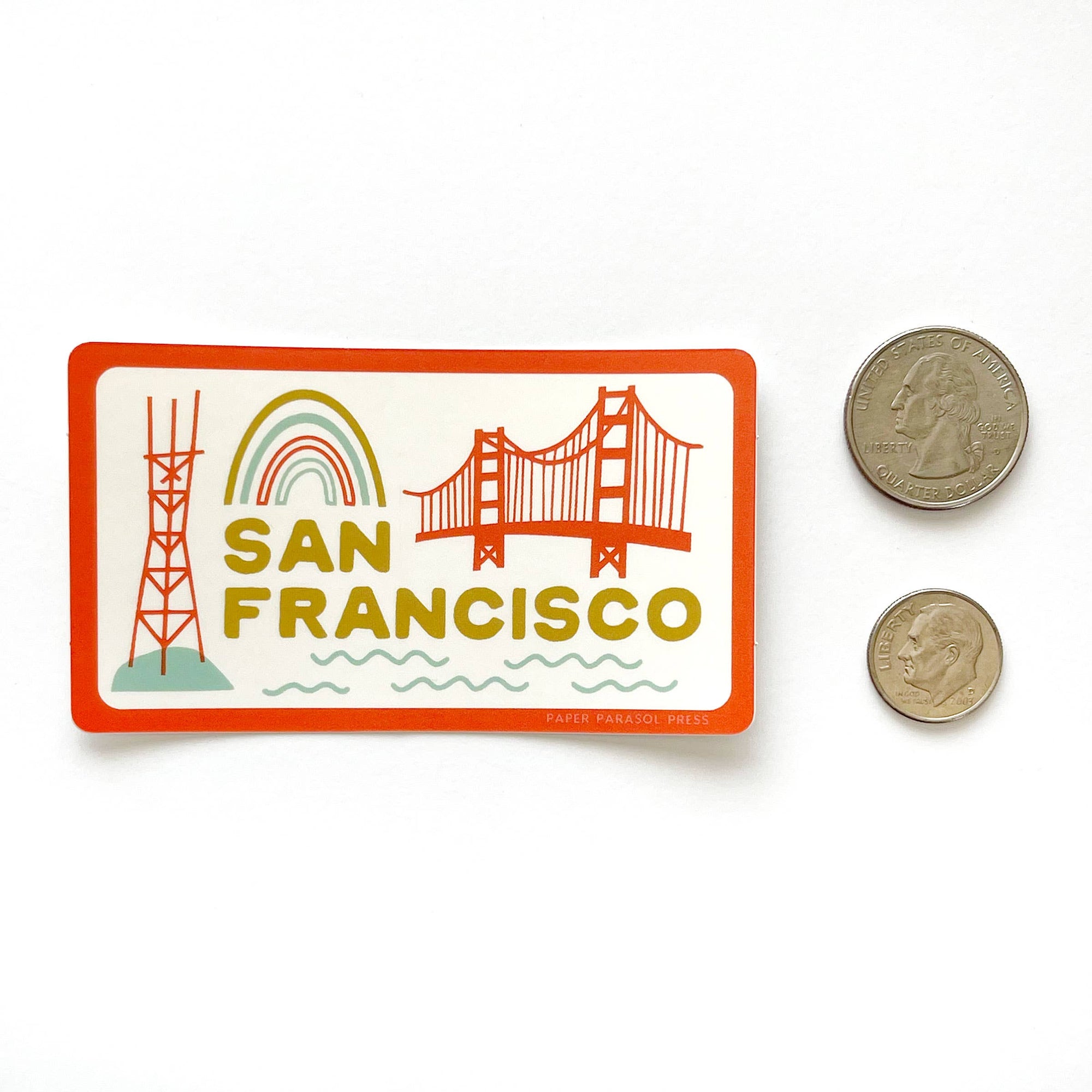 Sticker with San Francisco design featuring the Golden Gate Bridge and radio tower, next to two coins for scale.