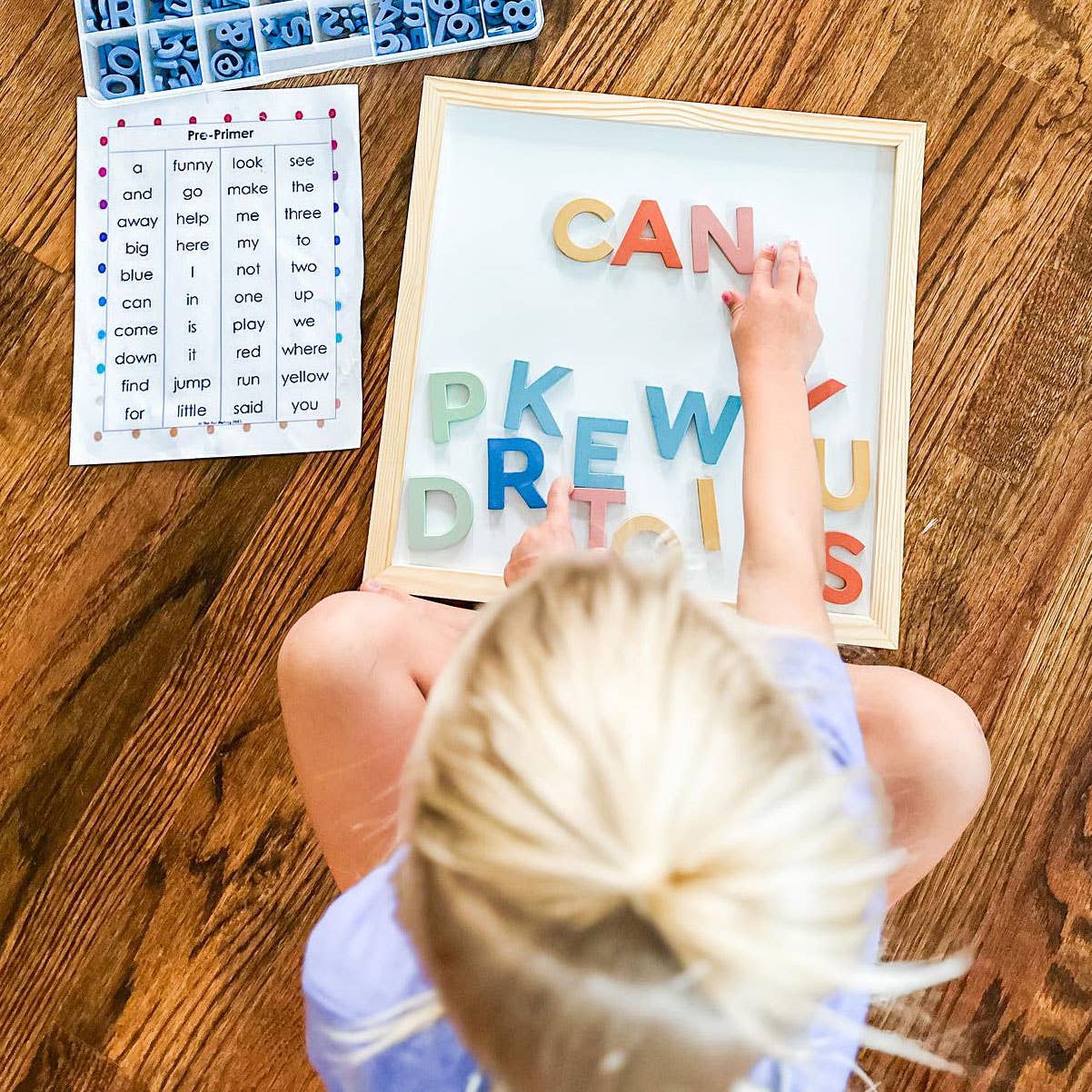 Child playing with a letter board on a wooden floor