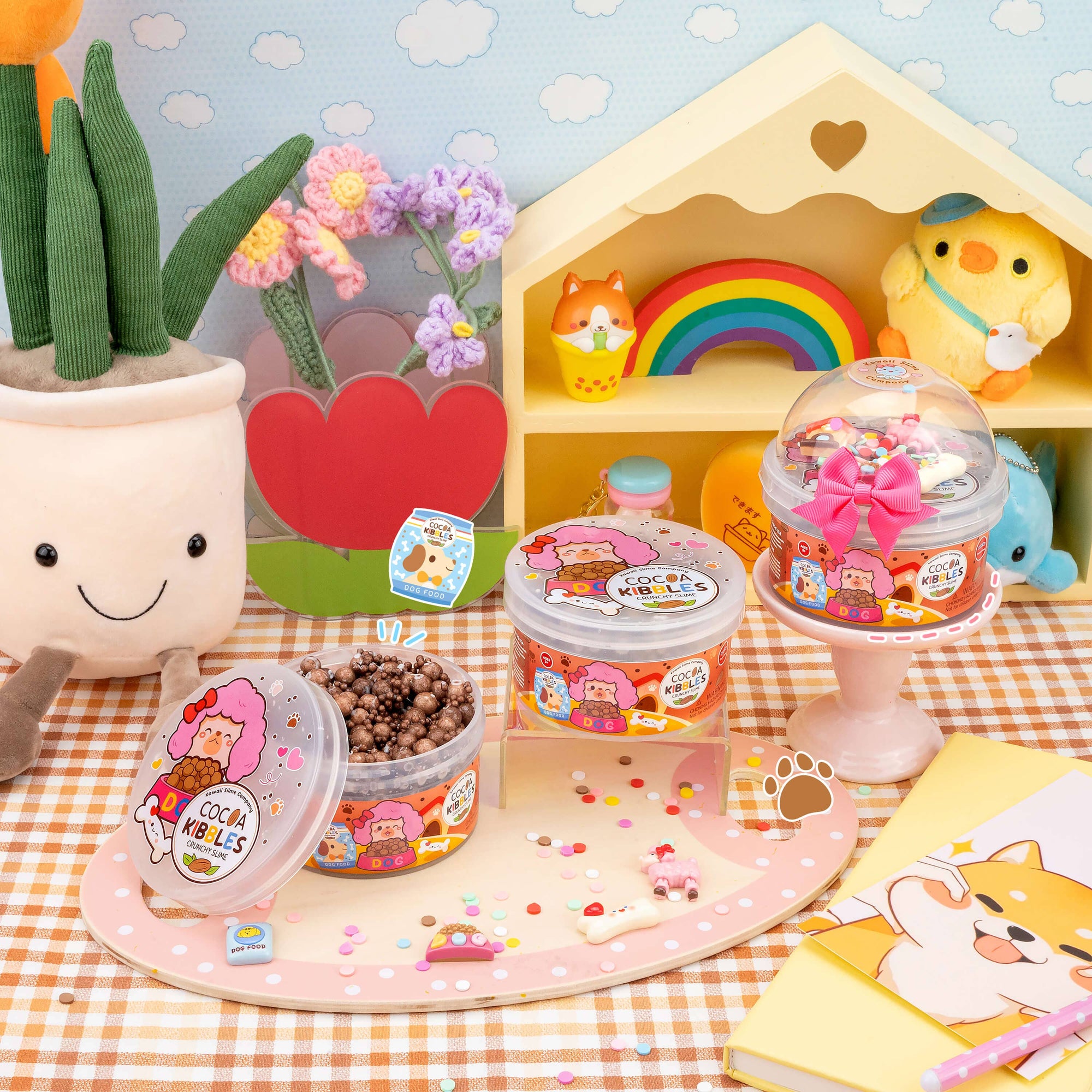 Cute toy setup with small containers, a rainbow, and plush toys on a checkered tablecloth.