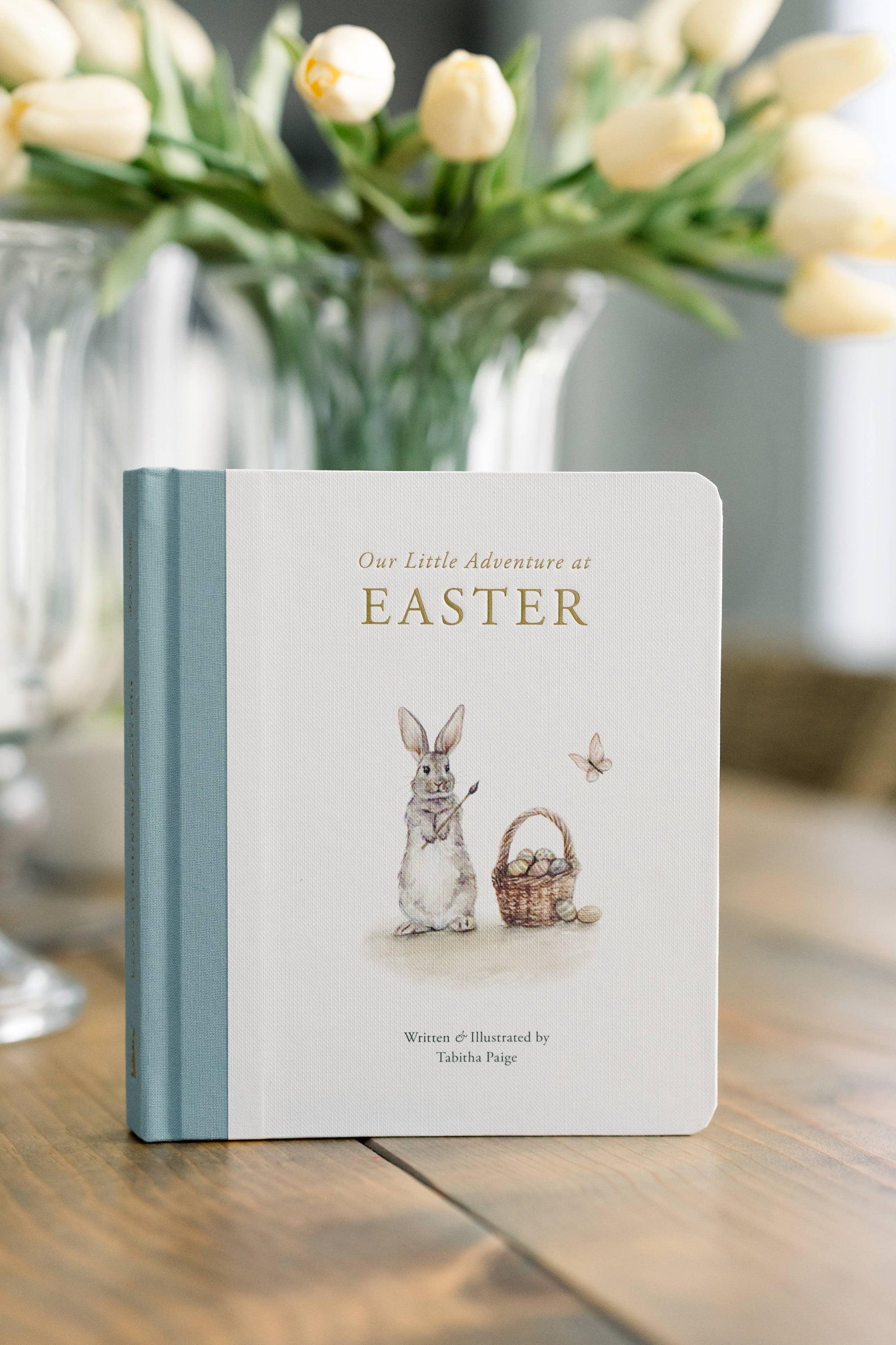 Book titled 'Our Little Adventures at Easter' with a rabbit illustration on a wooden table.
