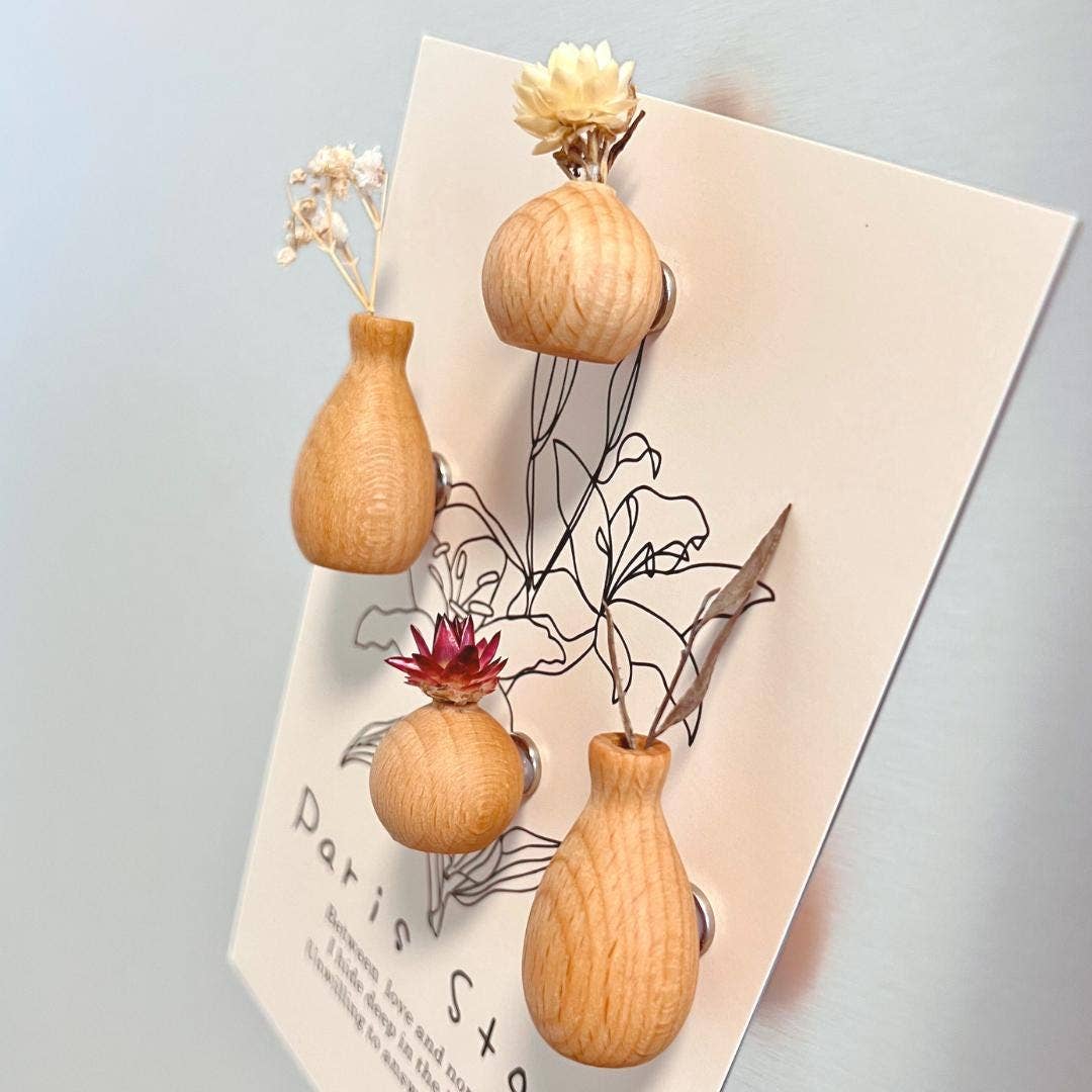 Three wooden vase-shaped earrings with dried flowers, displayed on a white card against a light blue-gray background.