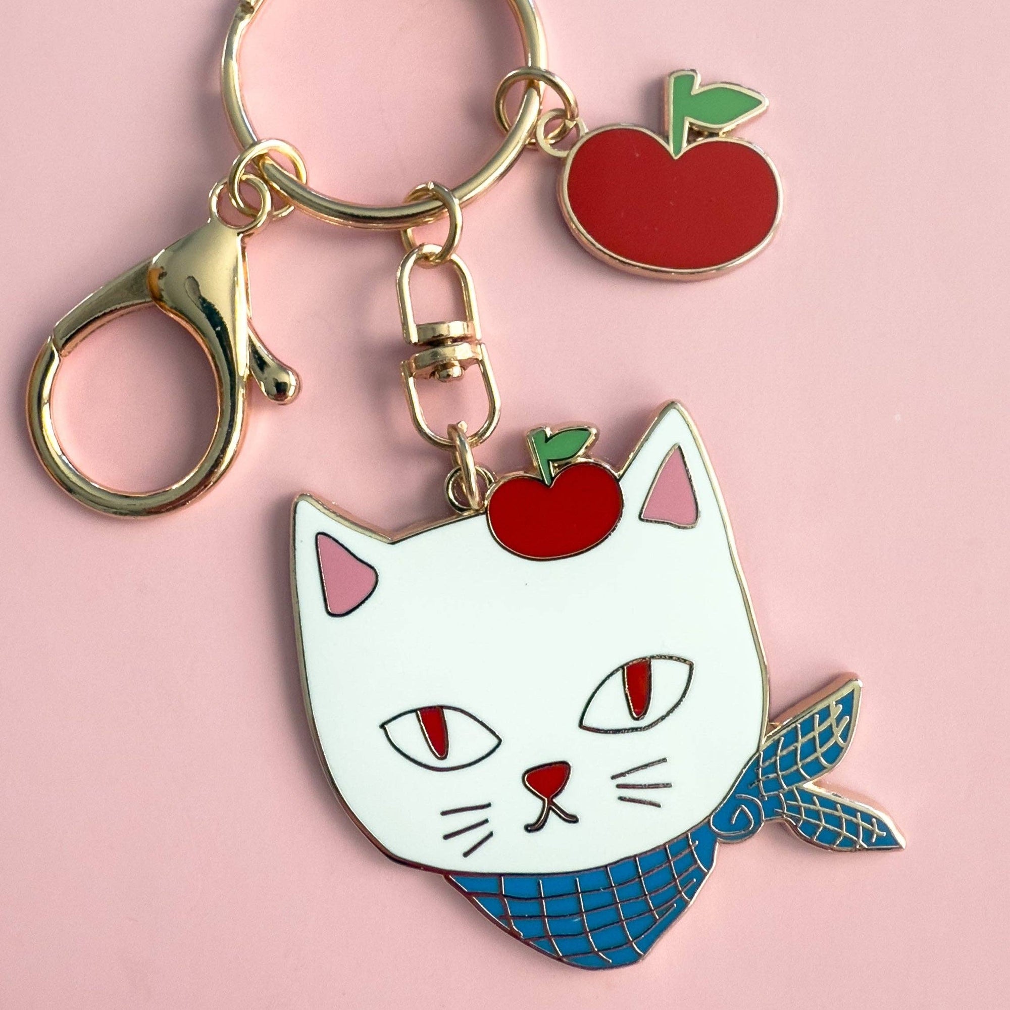 Keychain with a cat-like character and apple on a pink background