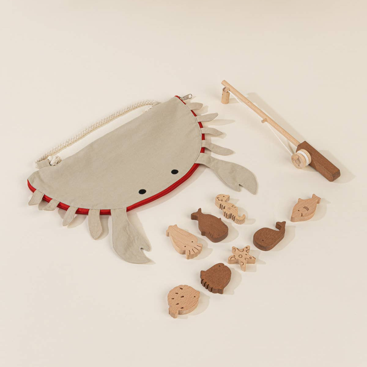 Decorative mat with a crab design and small wooden fish and fishing pole on a beige background