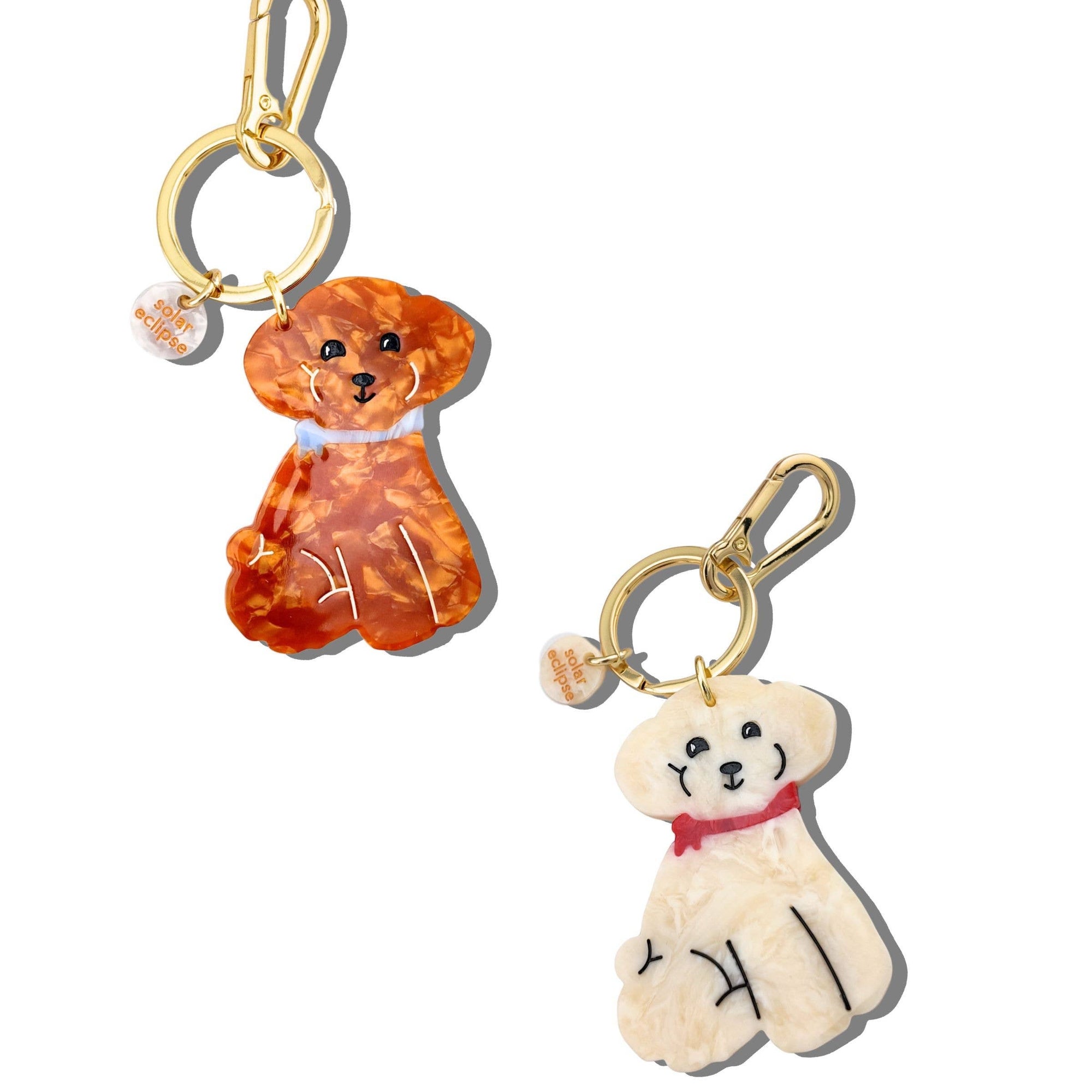 Two dog-shaped keychains, one orange and one white, on a white background.