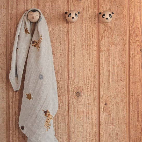 Decorative towel with embroidered pandas hanging on wooden hooks against a wooden wall.