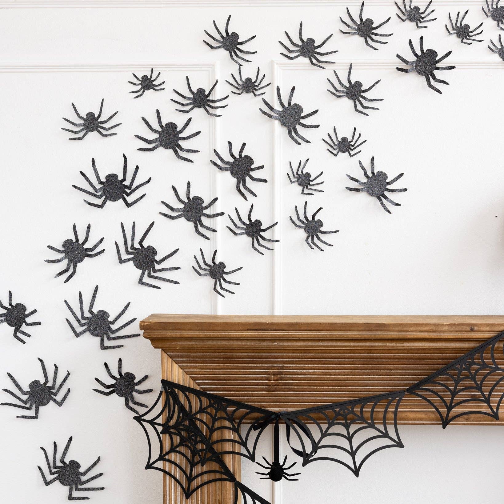 Halloween decorations with black spiders and webs on a white wall.