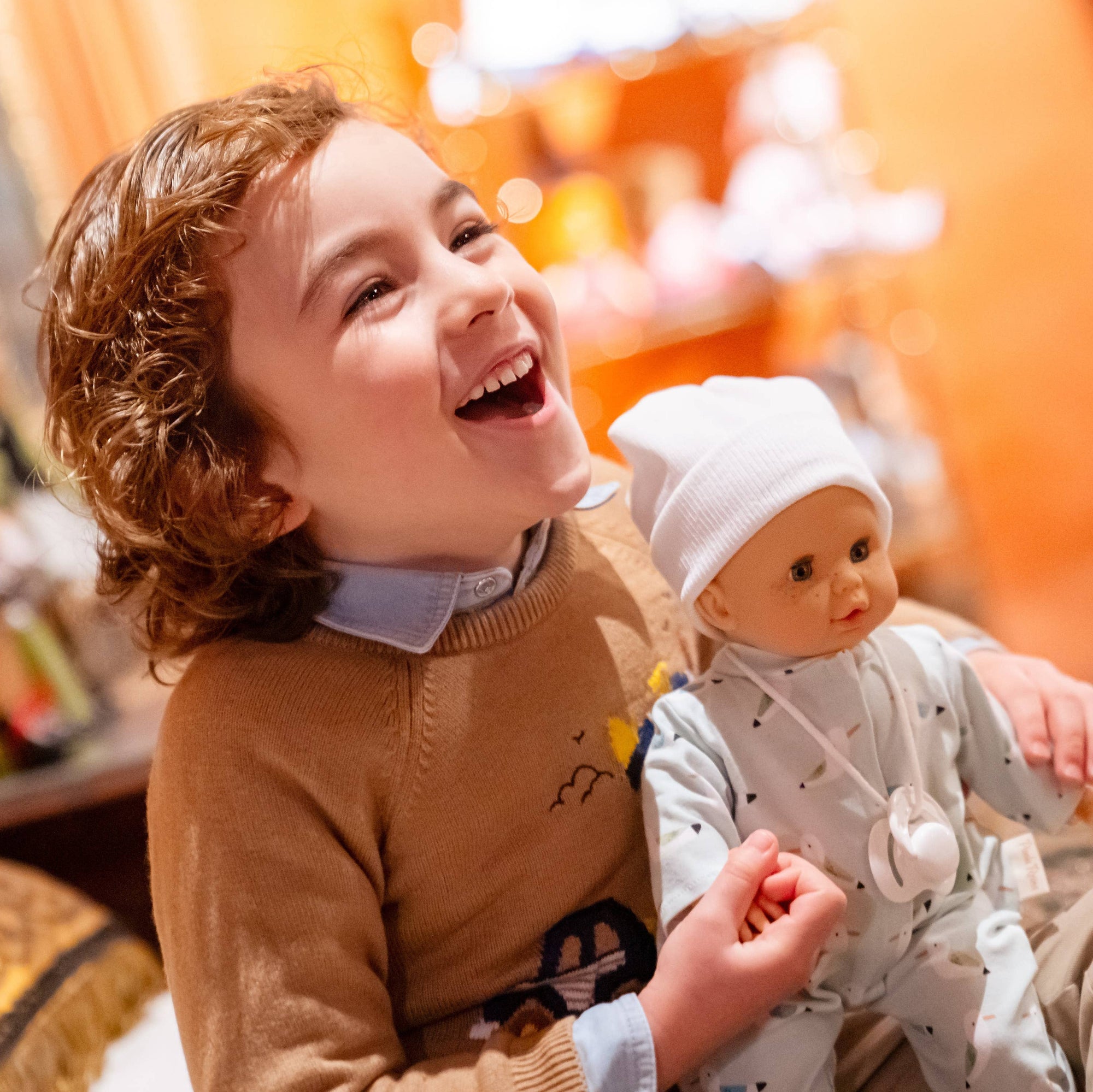 Child holding a babydoll with a blurred indoor background