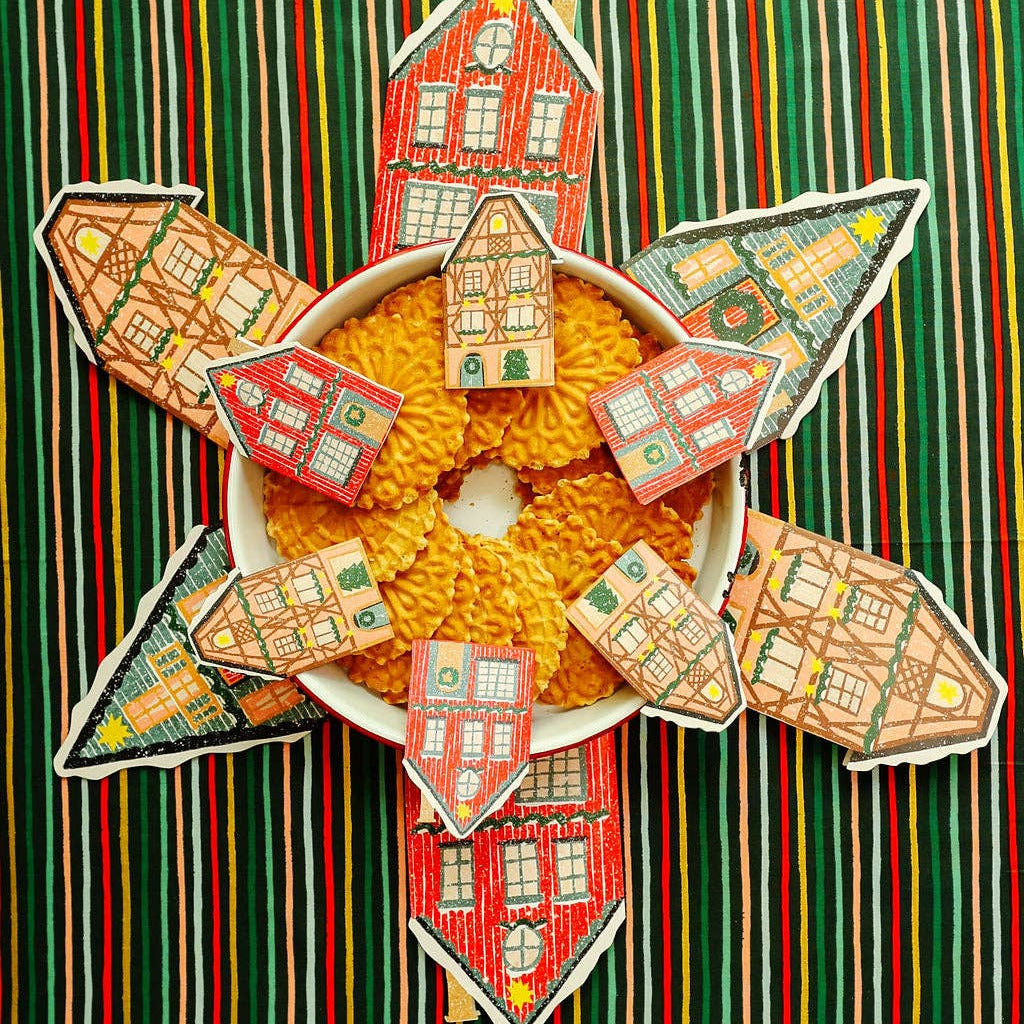 Decorative arrangement of small houses around a bowl of cookies on a striped background