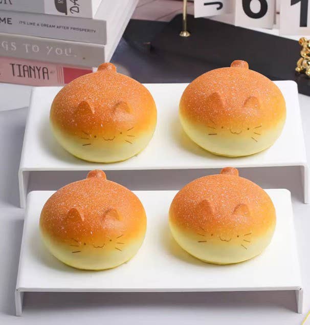 Four cat-shaped buns on a white stand with books in the background