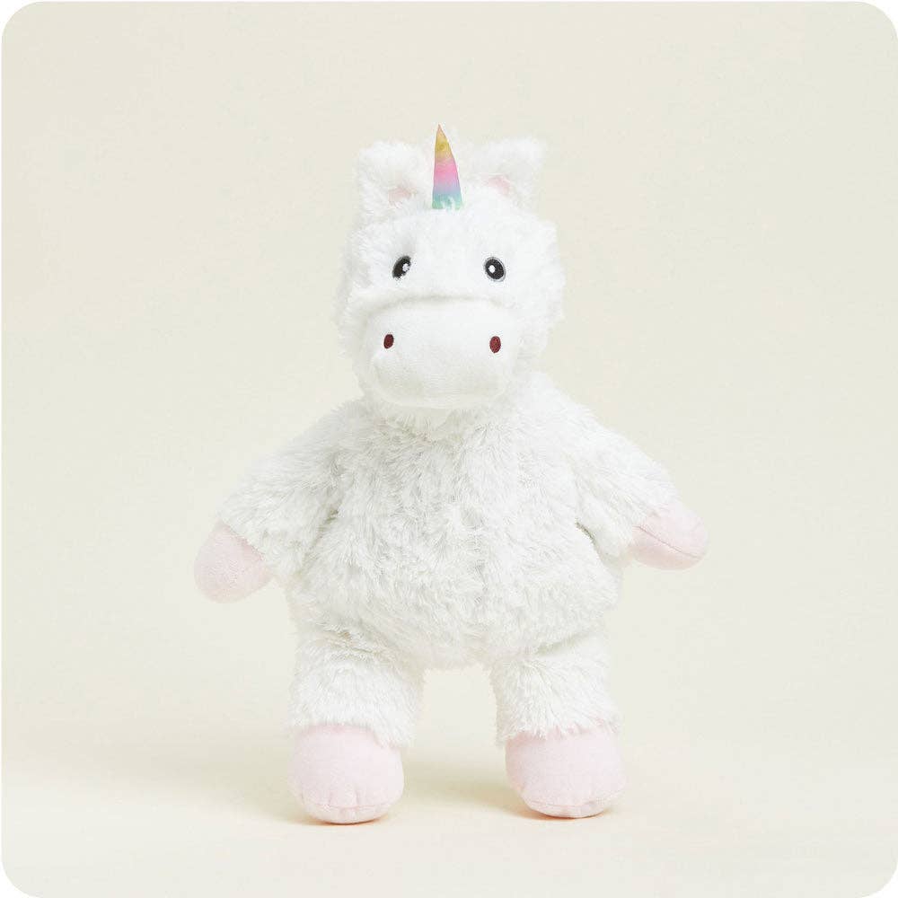Plush unicorn toy with a rainbow horn on a light beige background